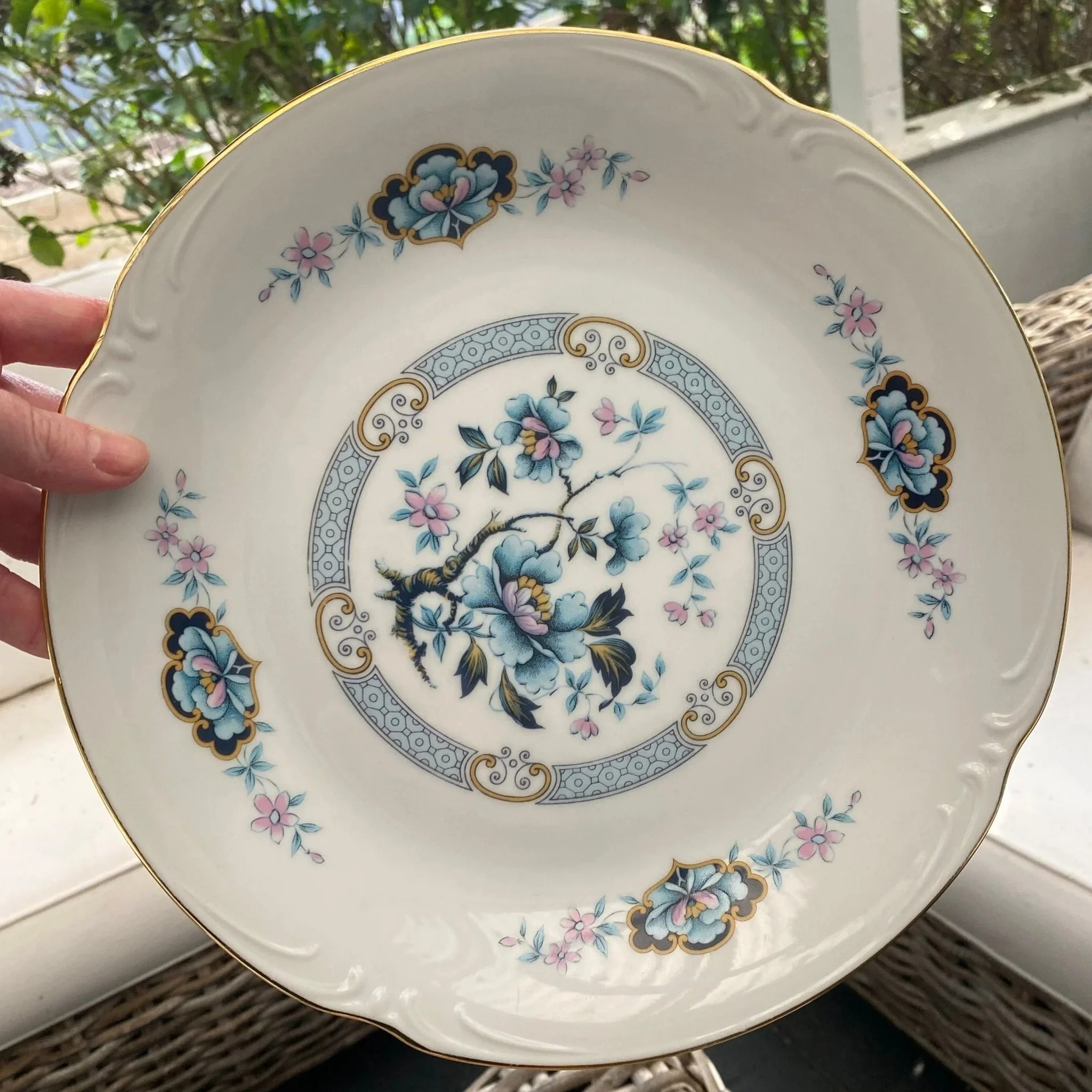 Hand-held view of the plate showing the full floral pattern and scalloped rim shape