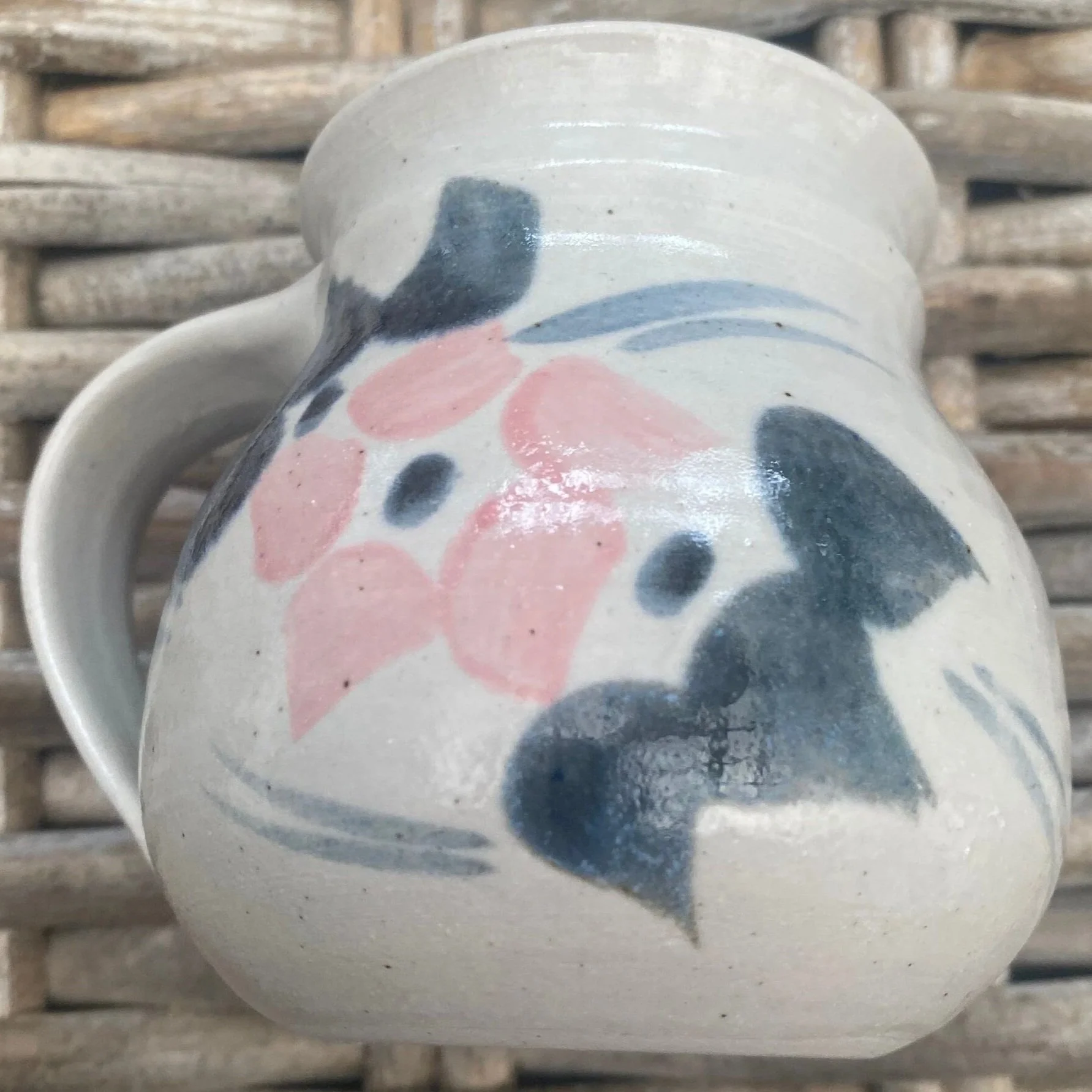 Side view of single mug highlighting floral brushstrokes in pink and navy