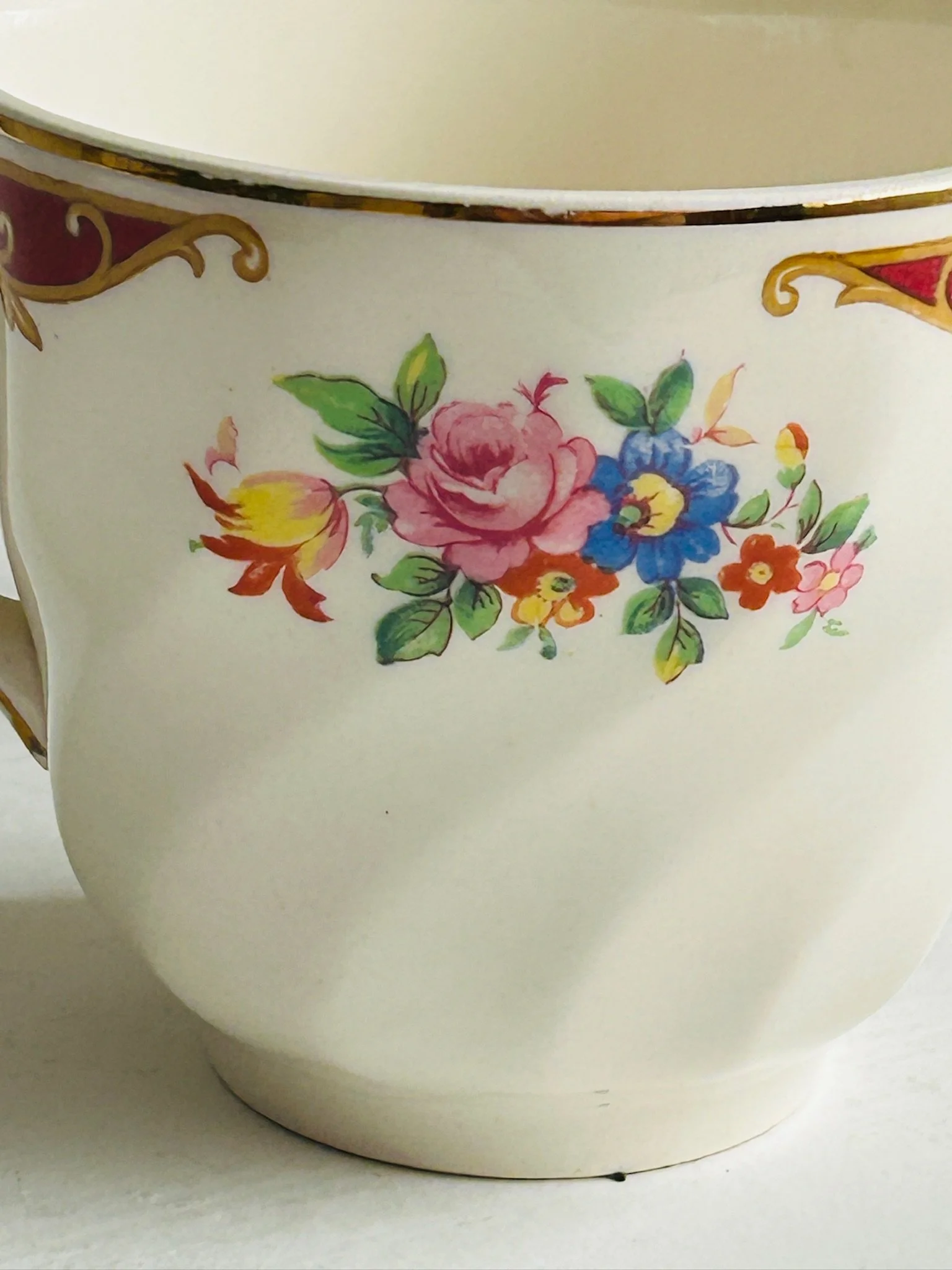 Close-up of the floral bouquet decoration and burgundy border with gold detailing on the teacup exterior