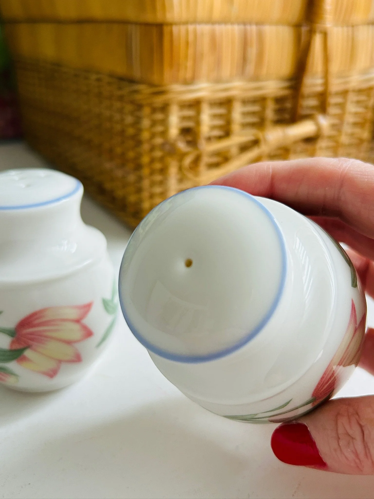 Top view of a single shaker held in hand, showing the one-hole top and pale blue rim