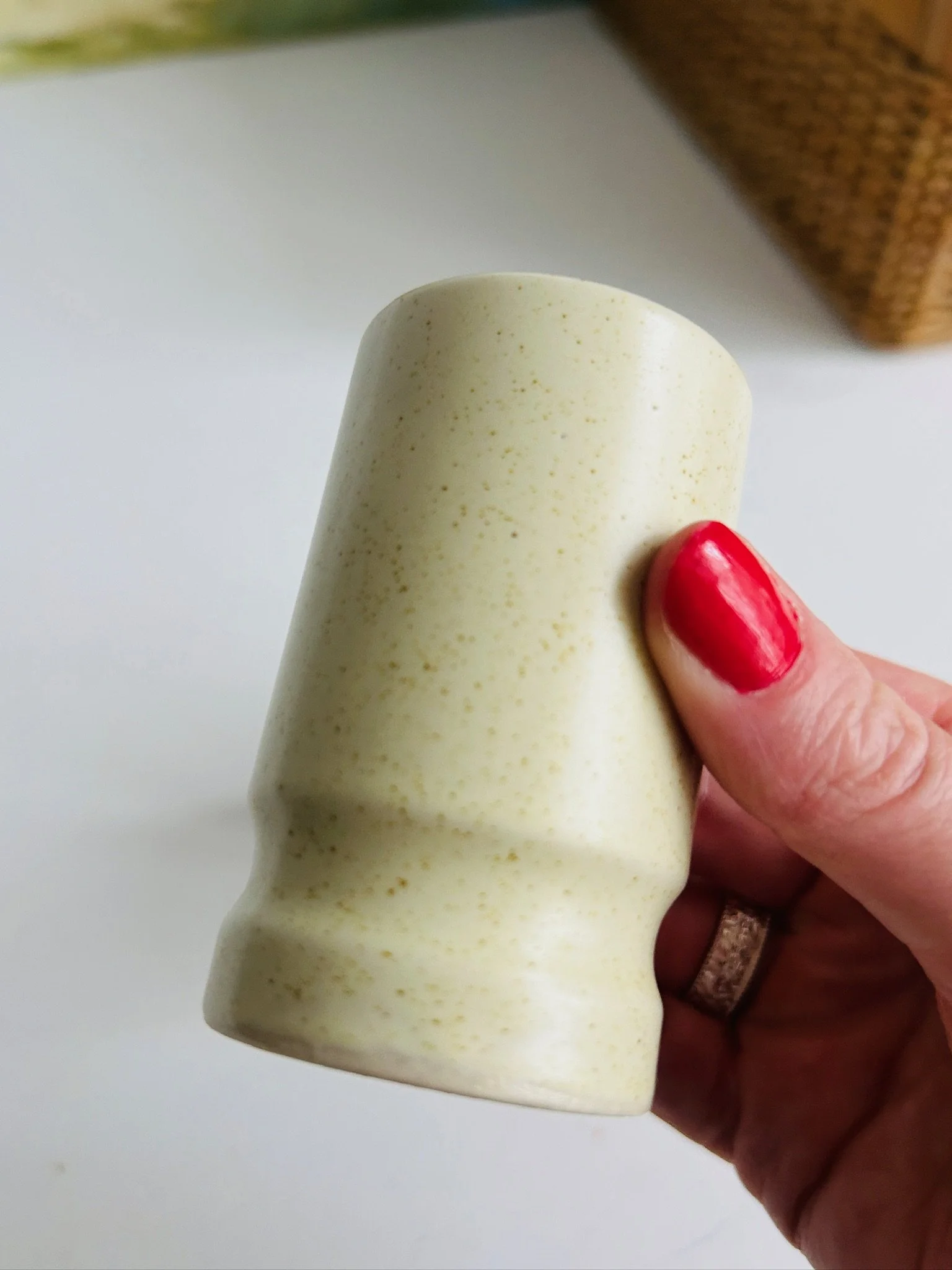 Single shaker held upside down in hand, showing the plain speckled body and stepped lower curve