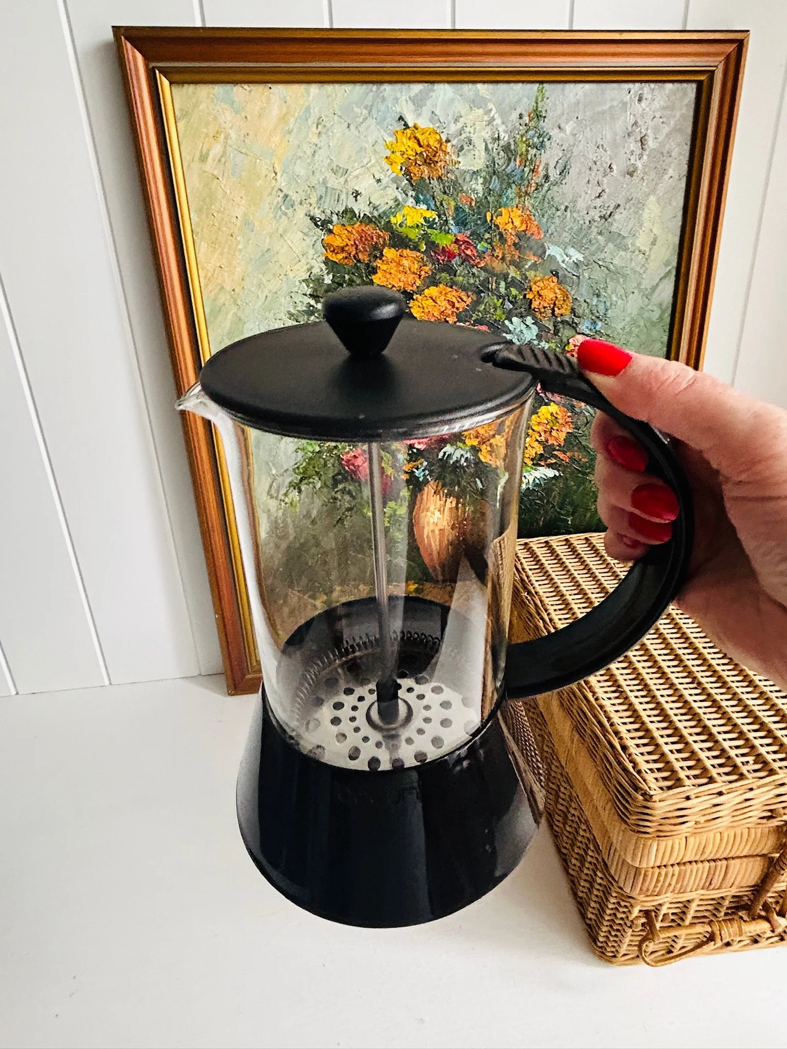 Front angle of the Bodum Presso French press held by the handle, showing the cylindrical glass carafe and plunger assembly inside.