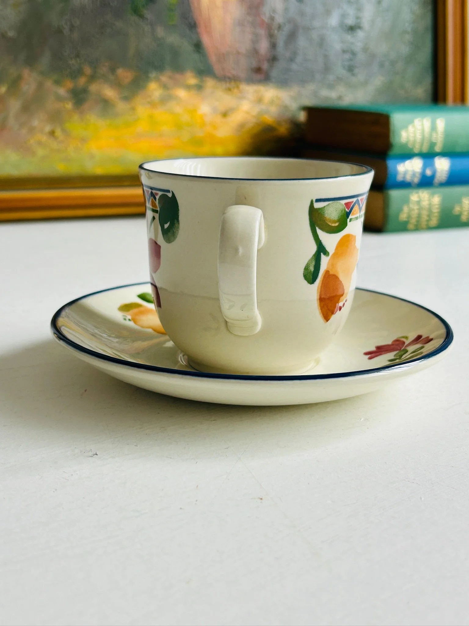 Rear view of the Staffordshire ‘Calypso’ tea cup on its saucer, showing the handle shape, side floral accents, and blue rim.