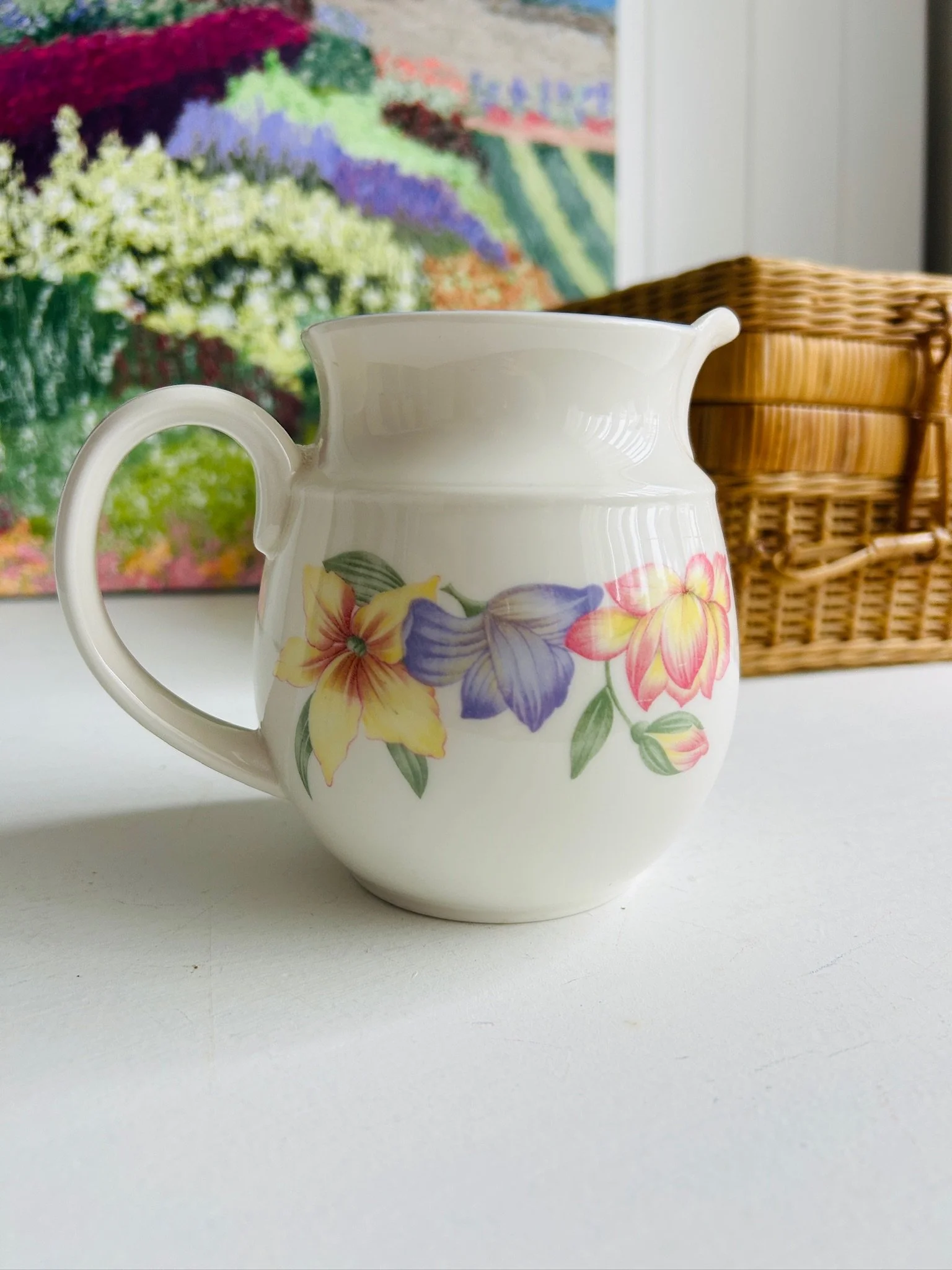 Angled front view of the floral creamer jug with handle and spout visible