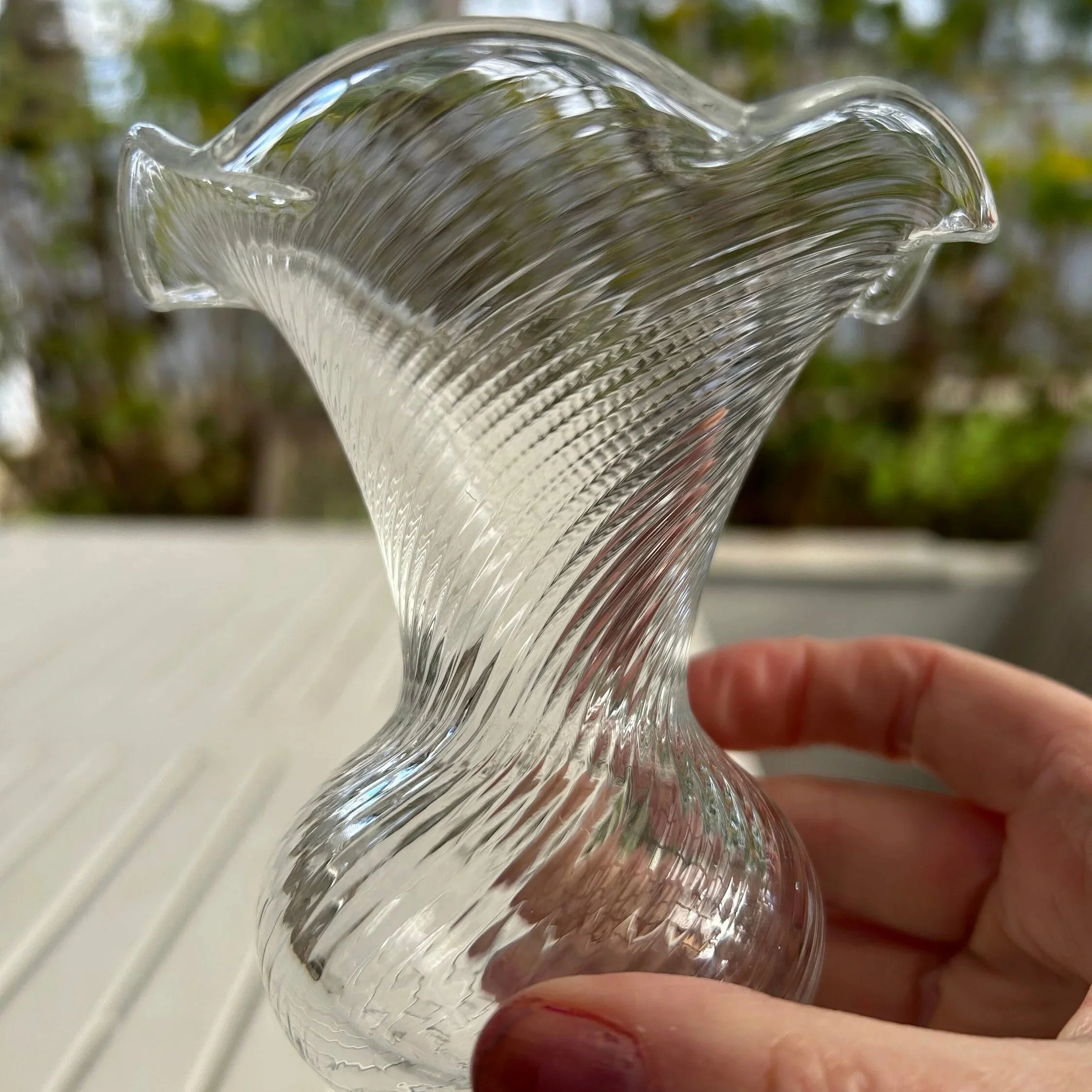 Profile of a single vase held to show delicate flared rim
