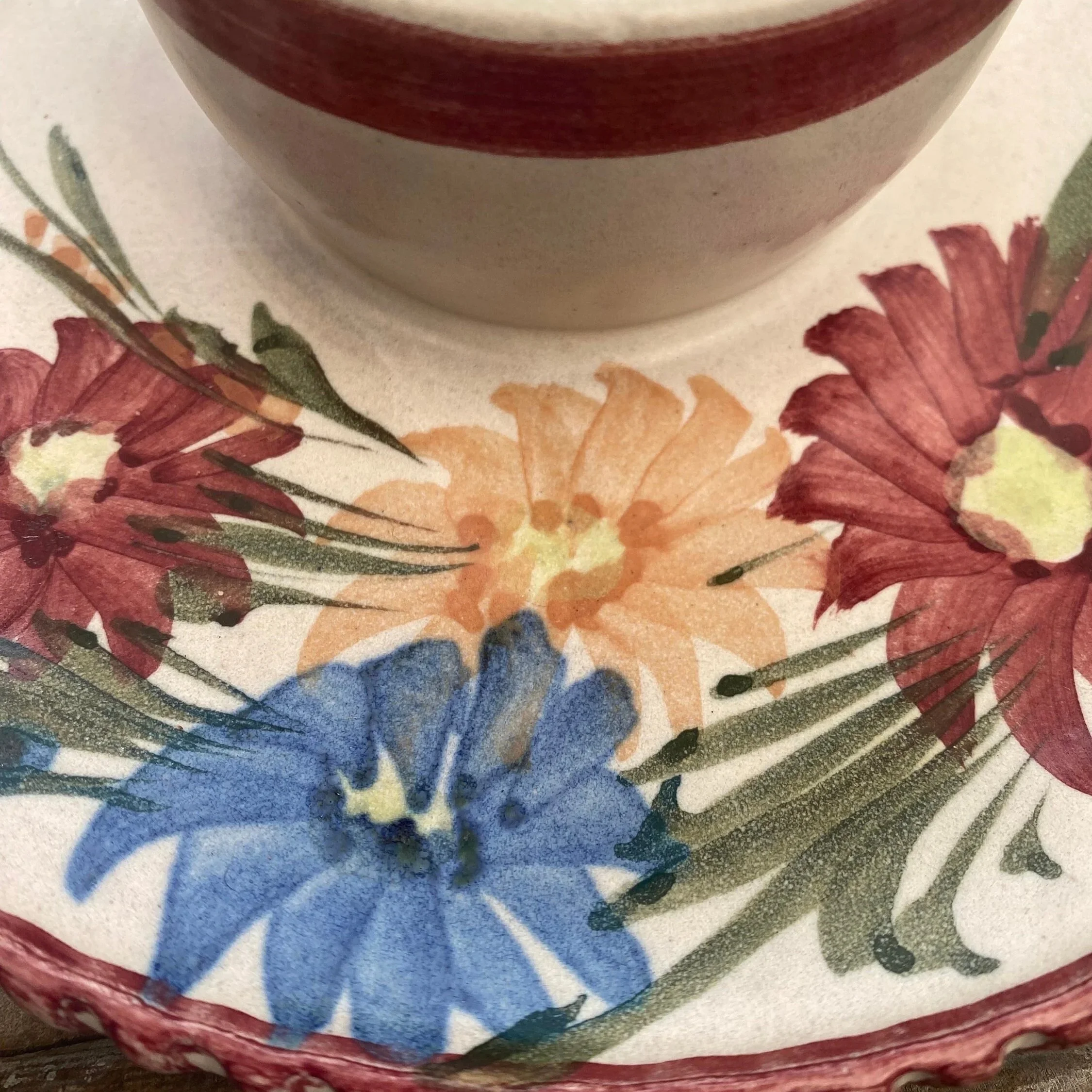 Close-up of hand-painted red, blue, and orange florals with green leaves