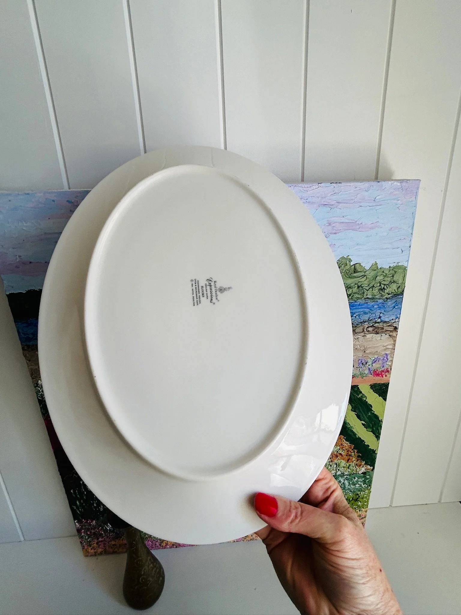 Underside of the vintage oval serving platter shown in hand, displaying the plain white base and central backstamp area