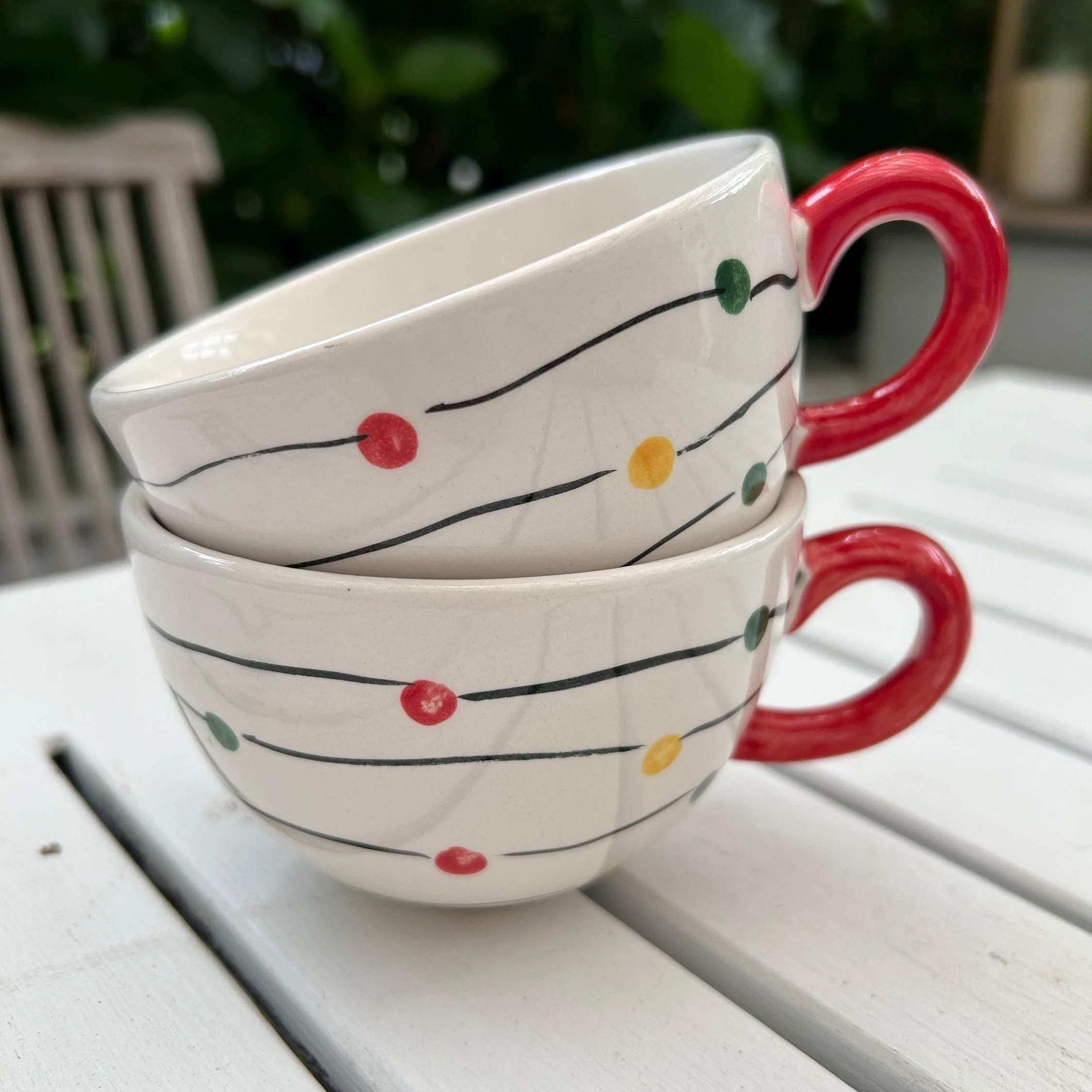 Pair of vintage Christmas mugs with colourful string lights and red handles.