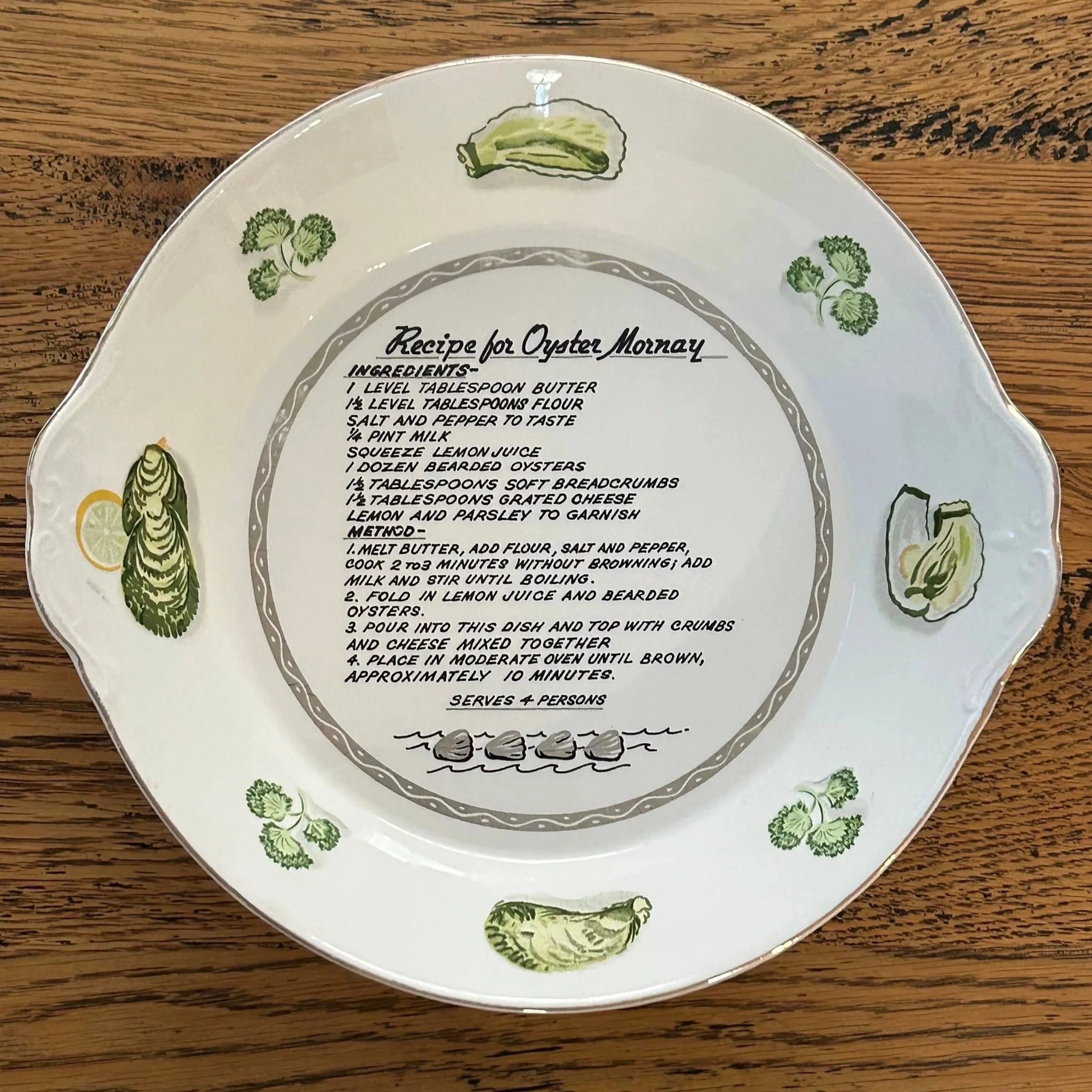 Overhead view of the full recipe dish with green oyster illustrations and Oyster Mornay recipe in the centre