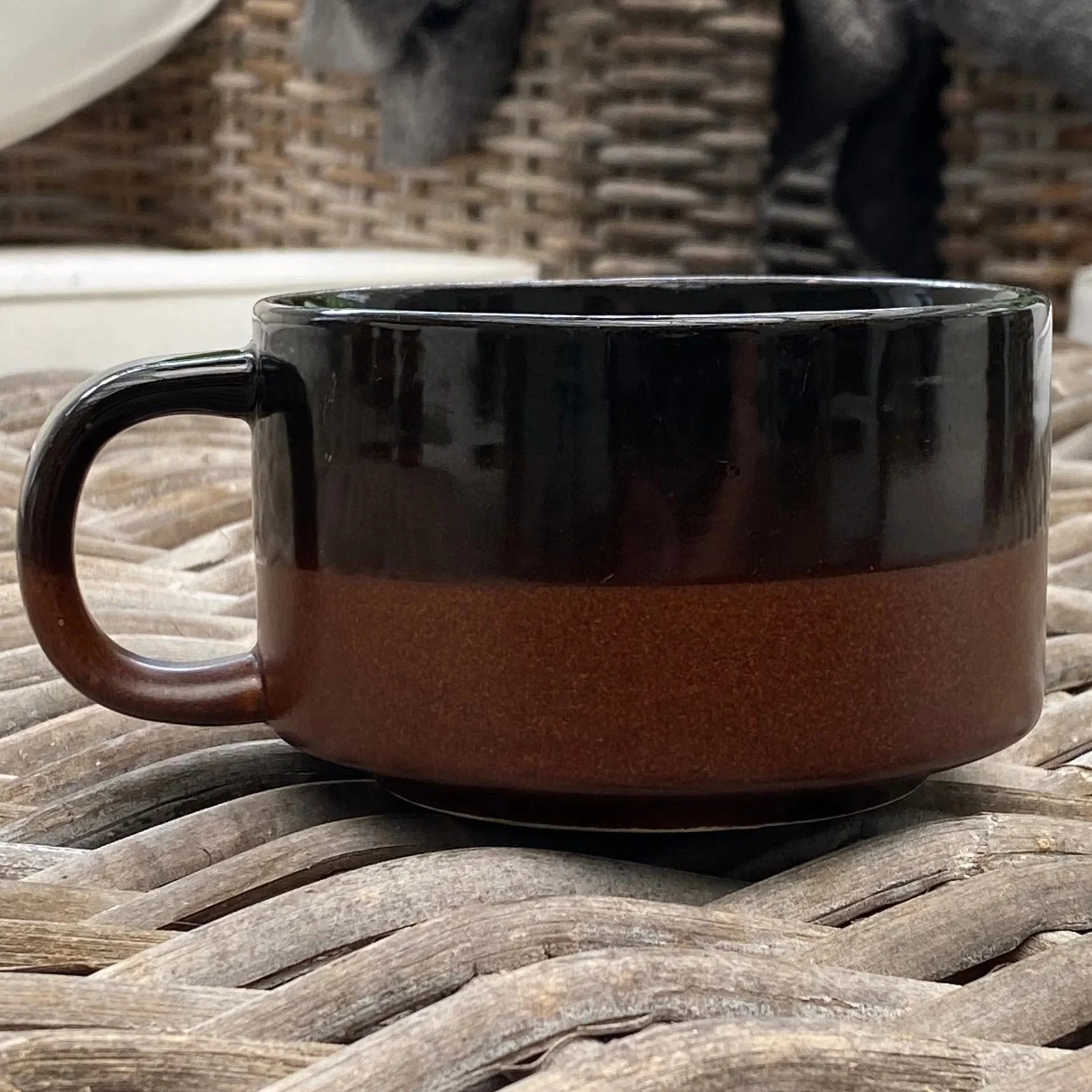 Side view of two-tone brown vintage Korean ceramic soup mug on wicker table
