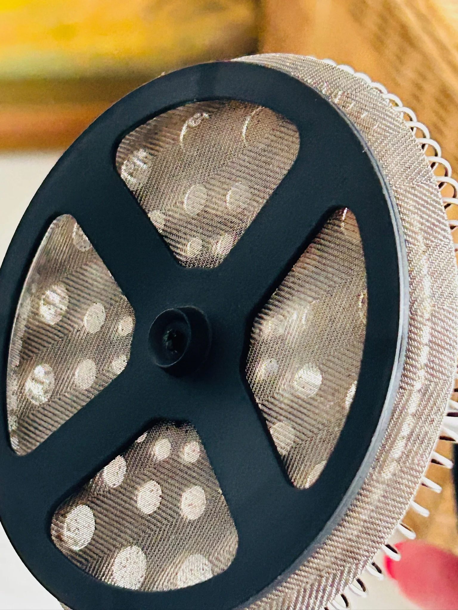 Underside view of the plunger filter assembly, showing the black cross support and fine metal mesh.