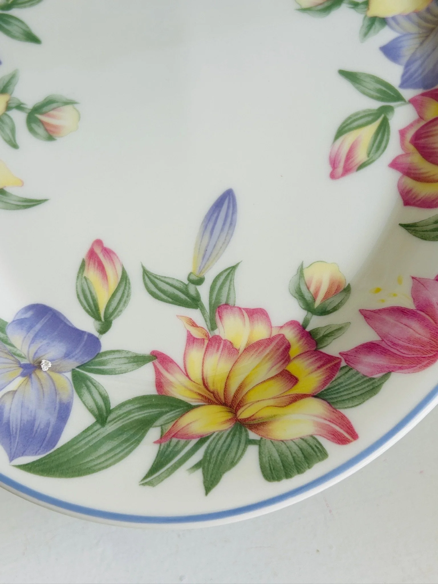 Close-up detail of the platter’s floral design, featuring yellow and pink blossoms, purple flowers, green leaves, and part of the blue rim