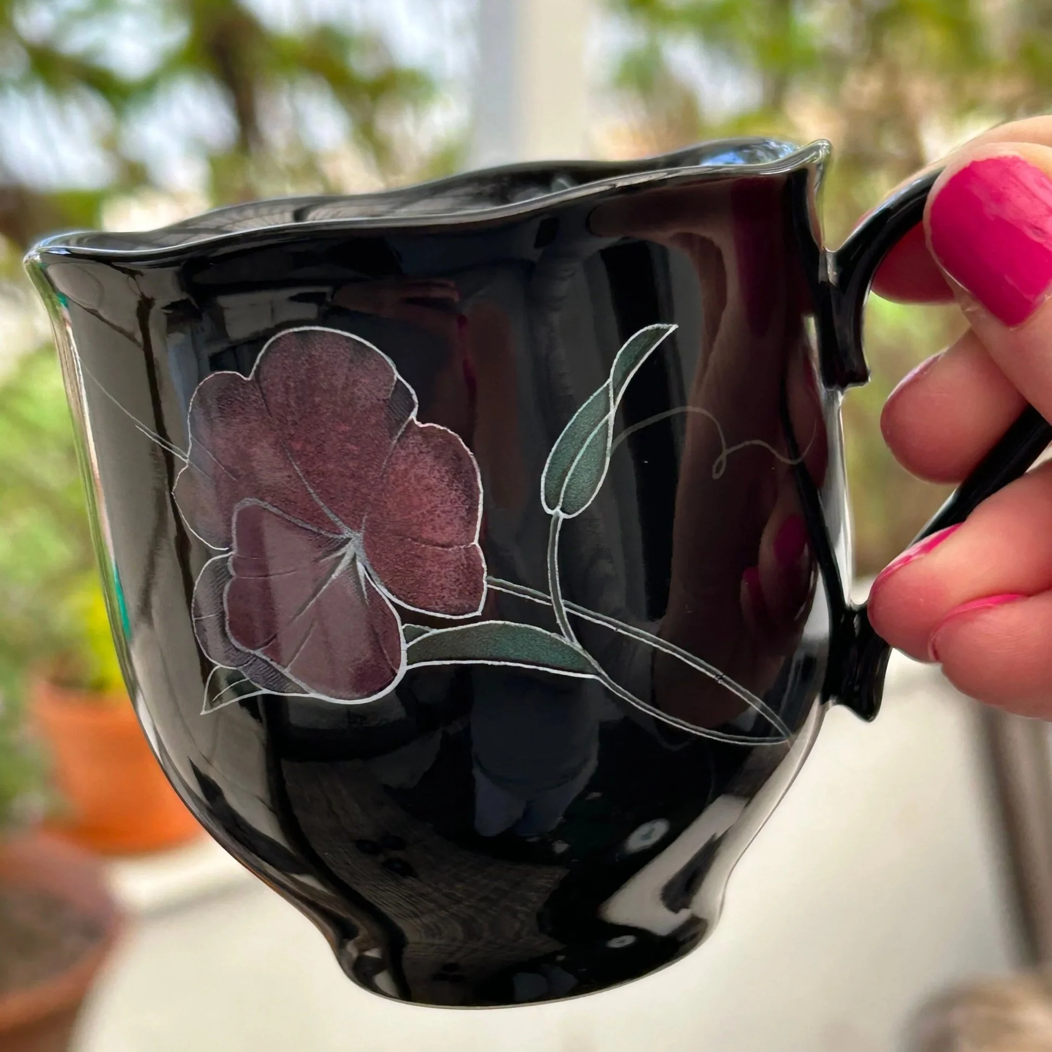 Mug held to the side – floral design and scalloped rim visible