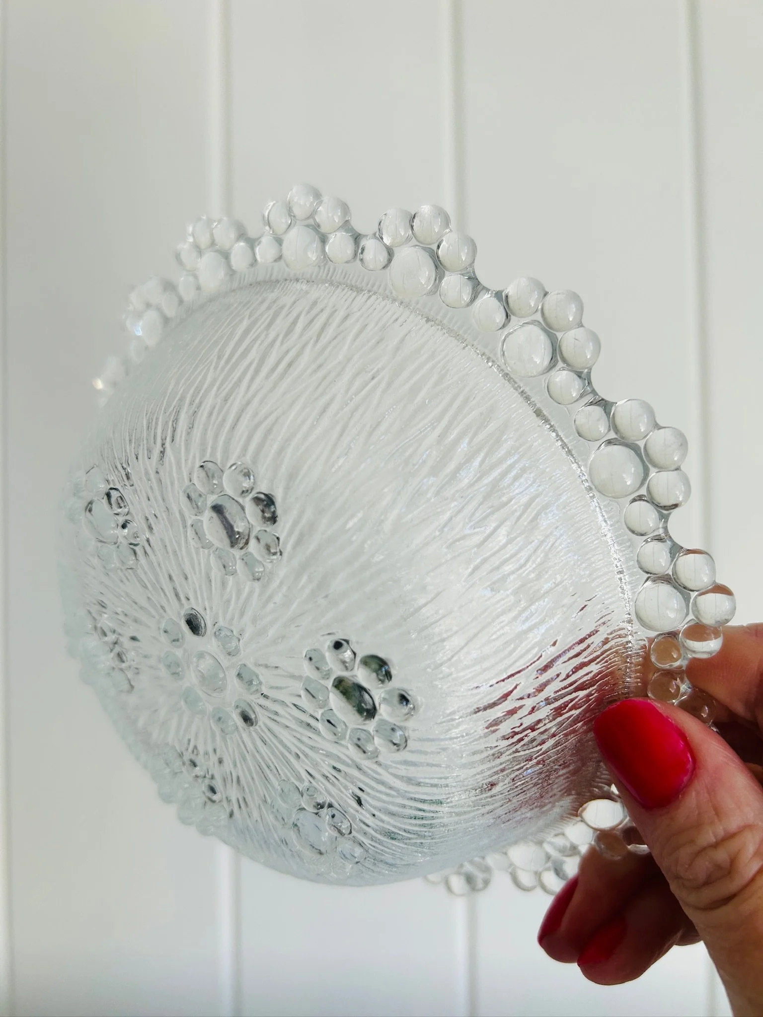Underside view of the bowl held in hand, showing the textured base and bubble rim from below.