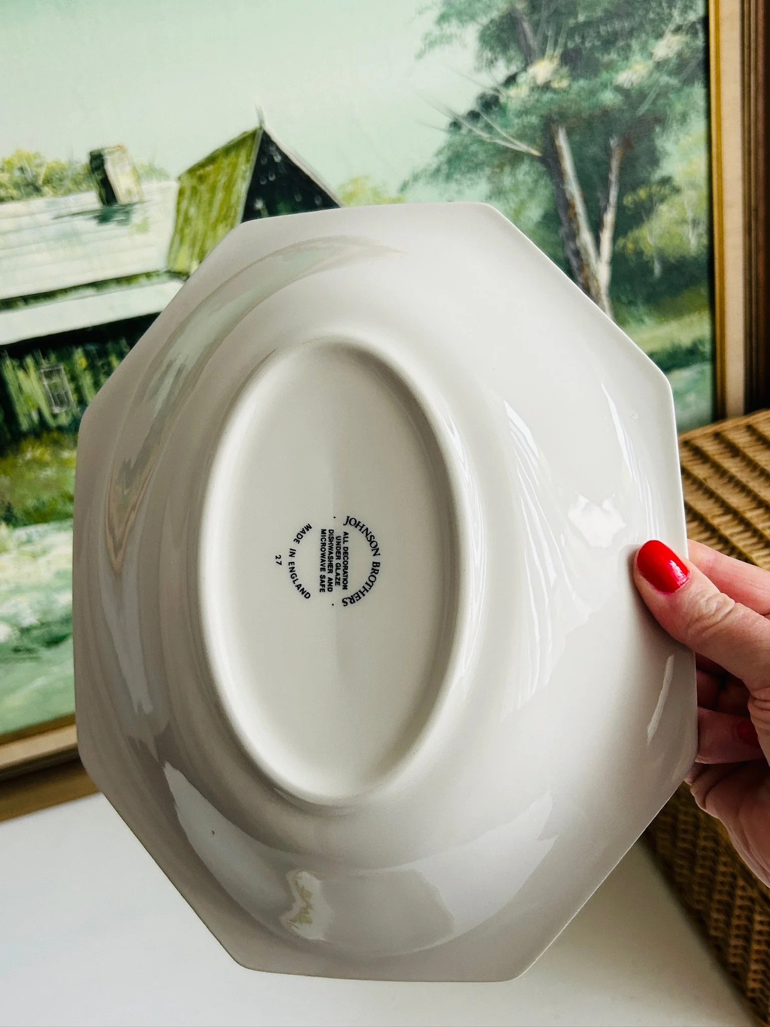 Underside view of one bowl held in hand, showing the octagonal footed base and printed maker’s mark.