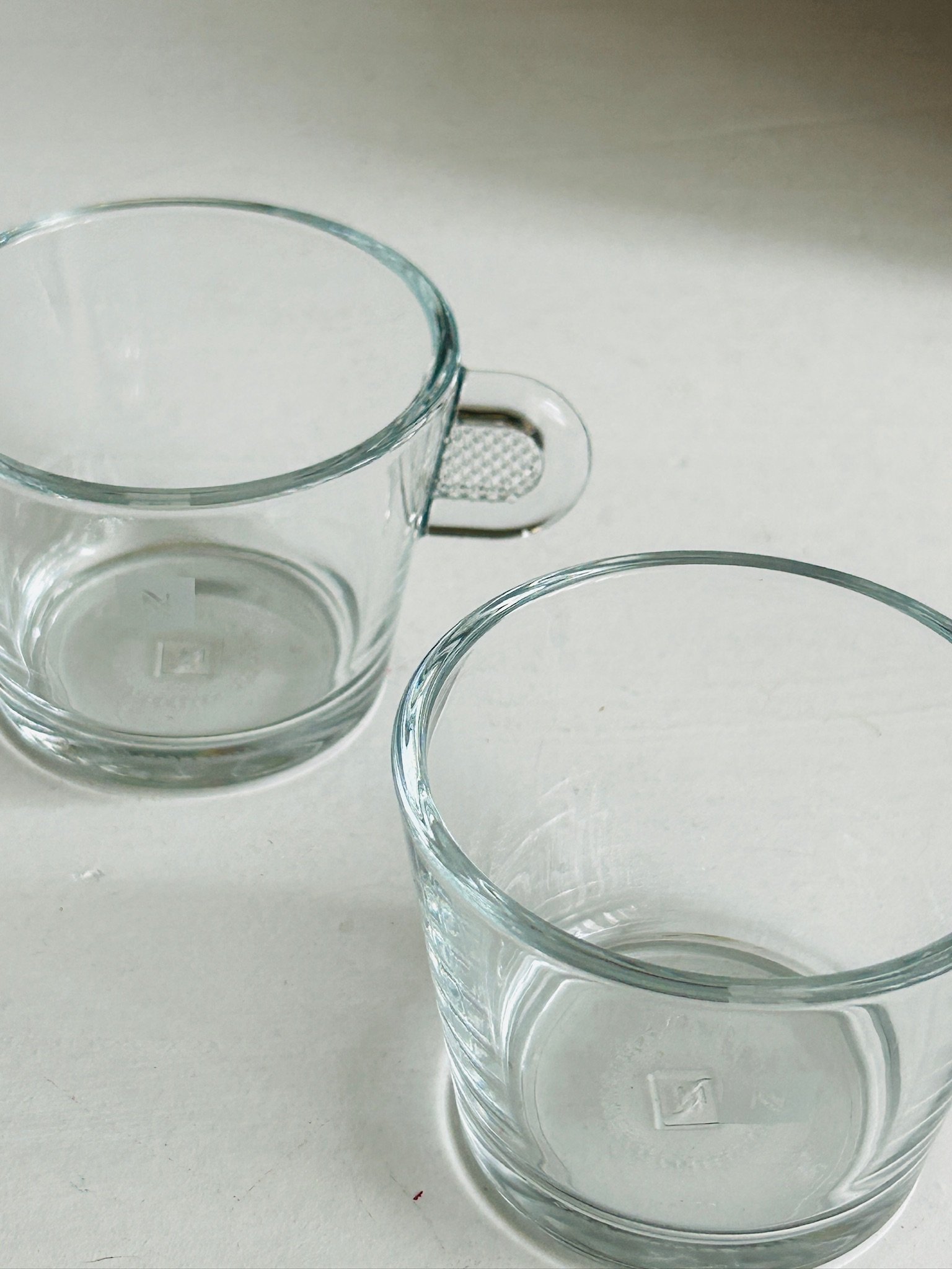 Two Nespresso glass espresso cups viewed from above at an angle, showing the cup openings and handles