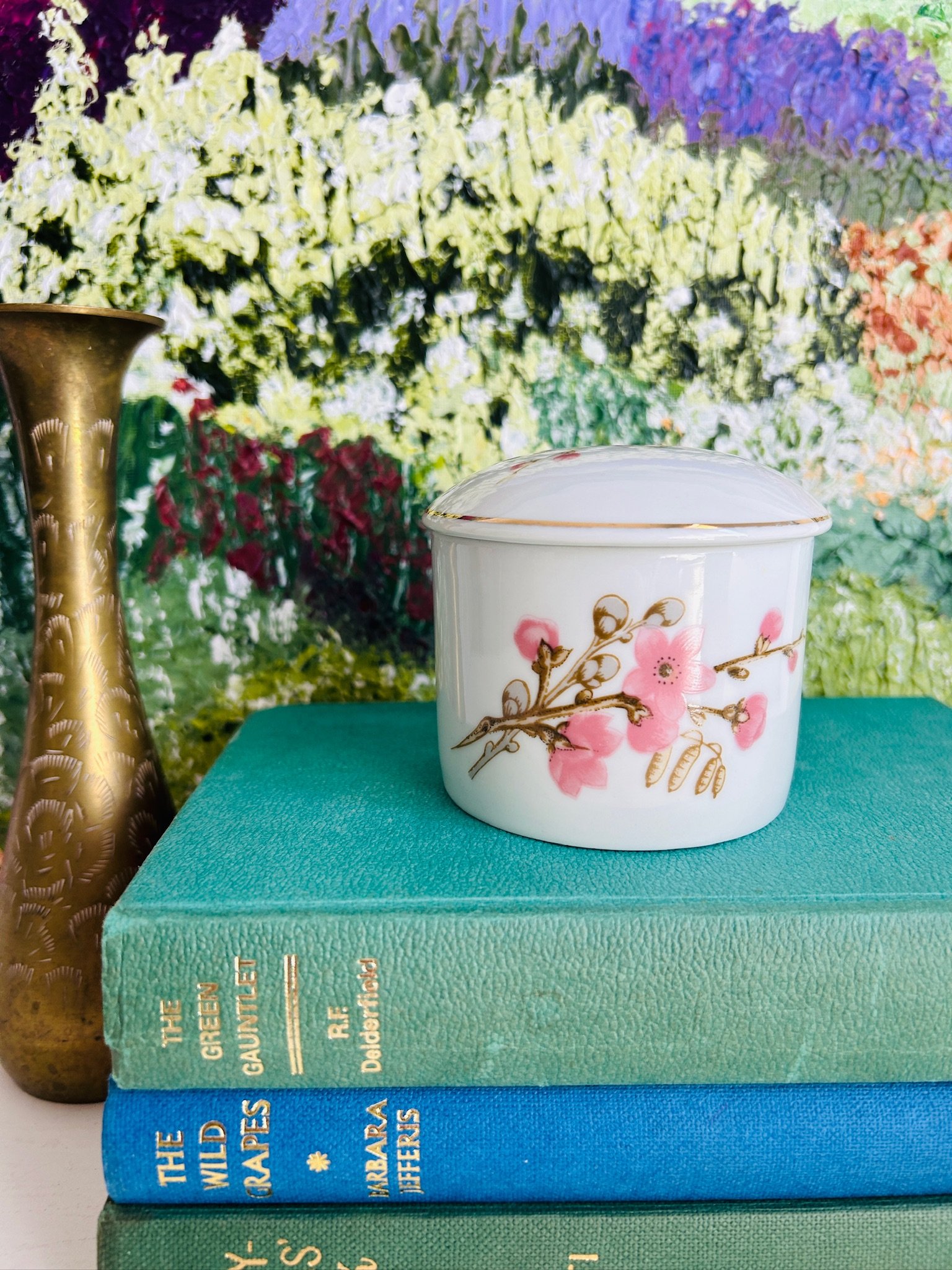 Vintage Porcelana Schmidt lidded trinket bowl displayed on stacked books, showing the white porcelain body, pink blossom design, and fine gold rim