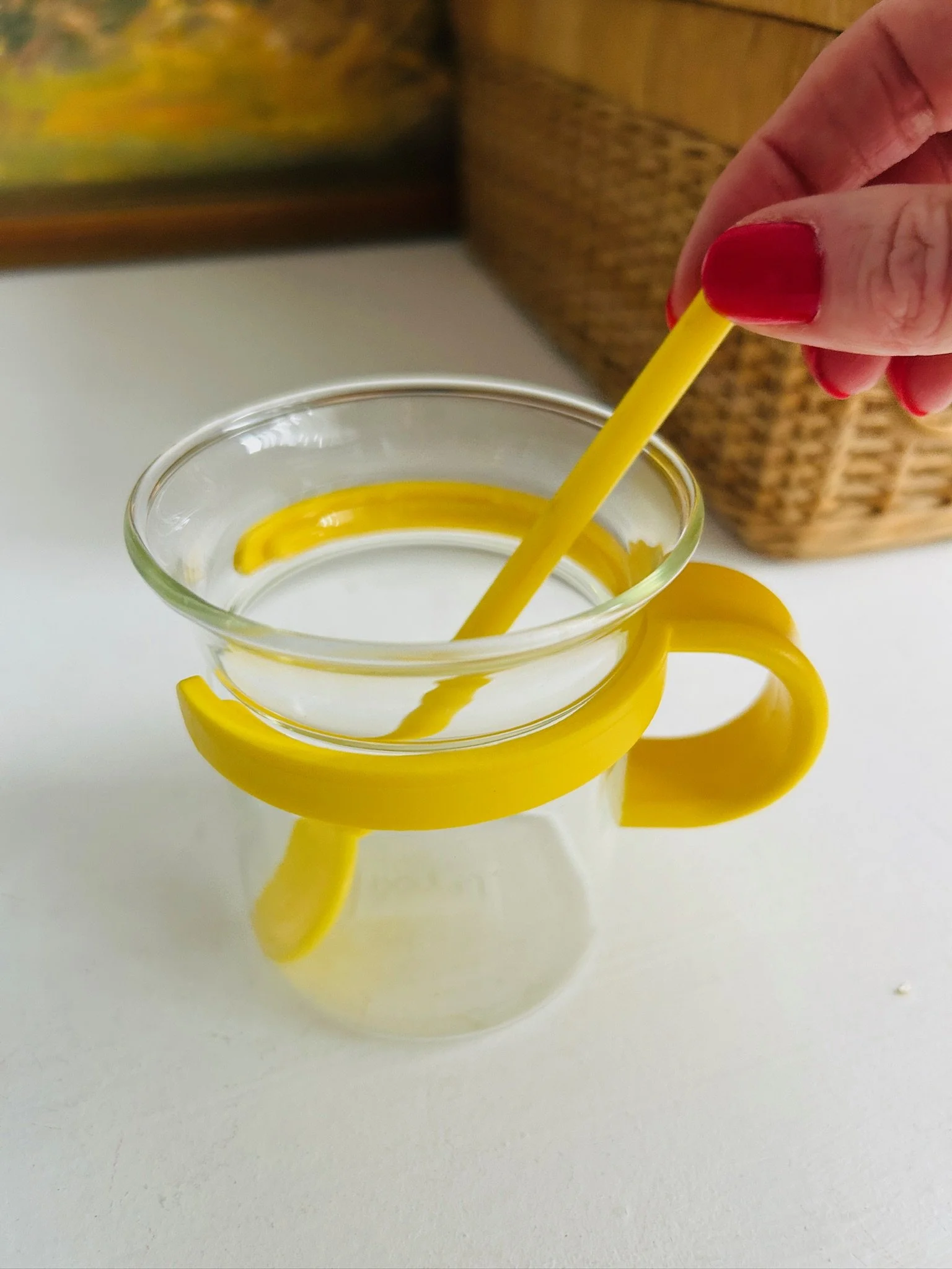 Close-up of a single yellow Bodum Picard cup with spoon inside, highlighting the bright plastic holder and clear glass form.