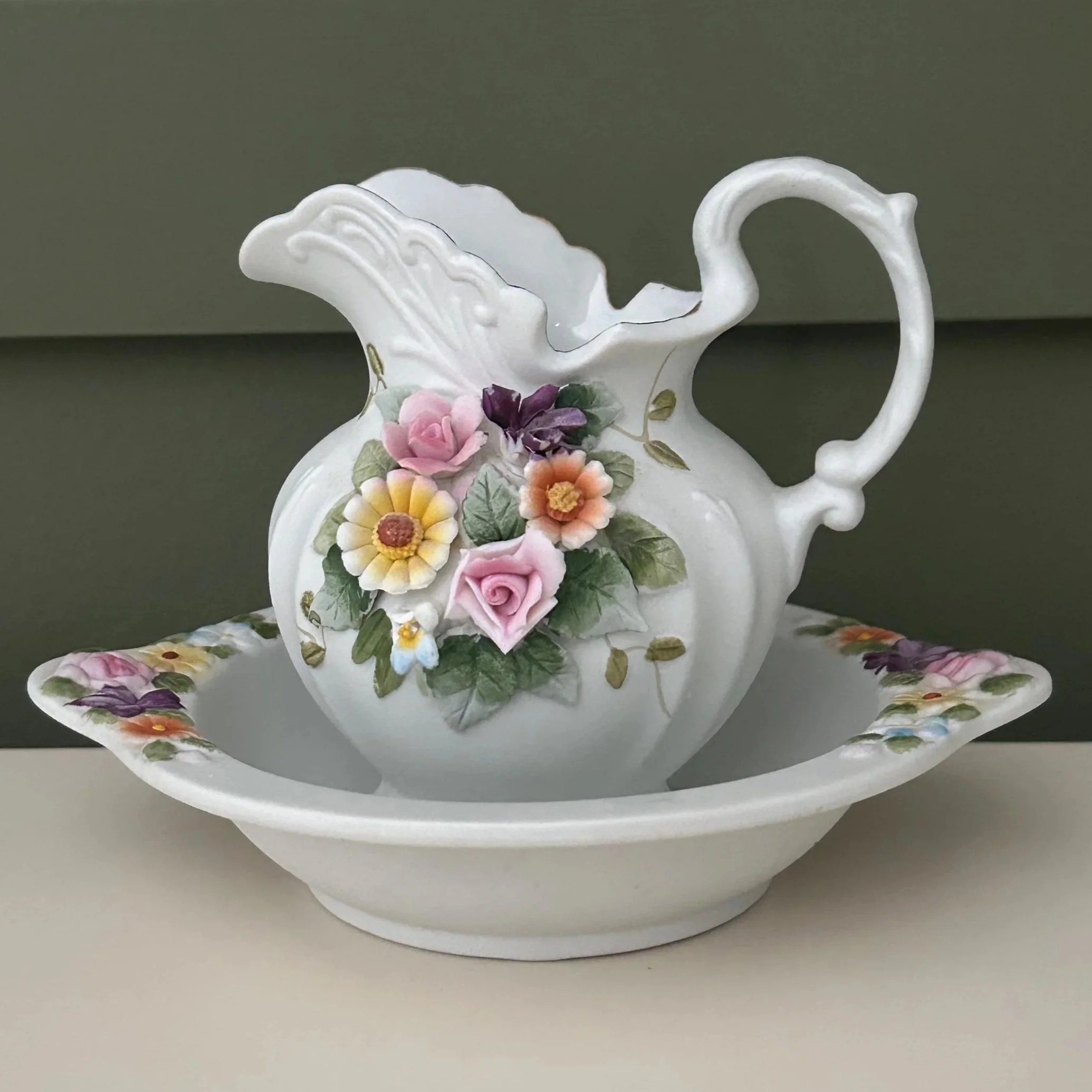 Jug and bowl close-up showing applied pastel floral detailing and scalloped handles