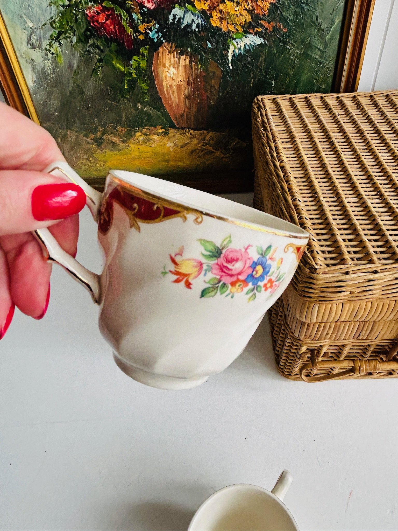 Side view of one floral English teacup held in hand, showing the bouquet motif and softly shaped body