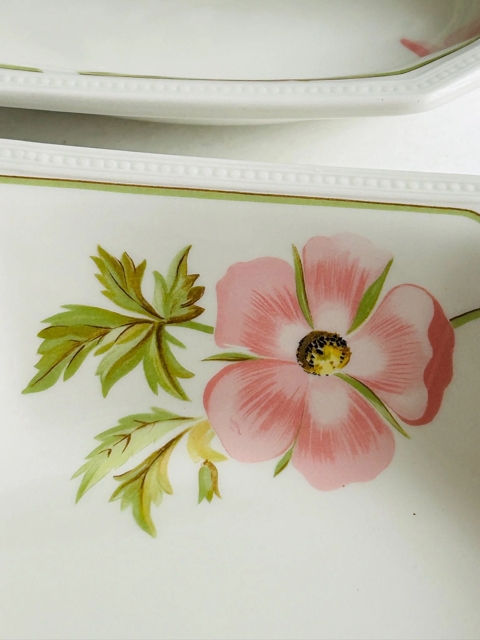 Close-up of the embossed rim and pink flower detail on the inside edge of one bowl.