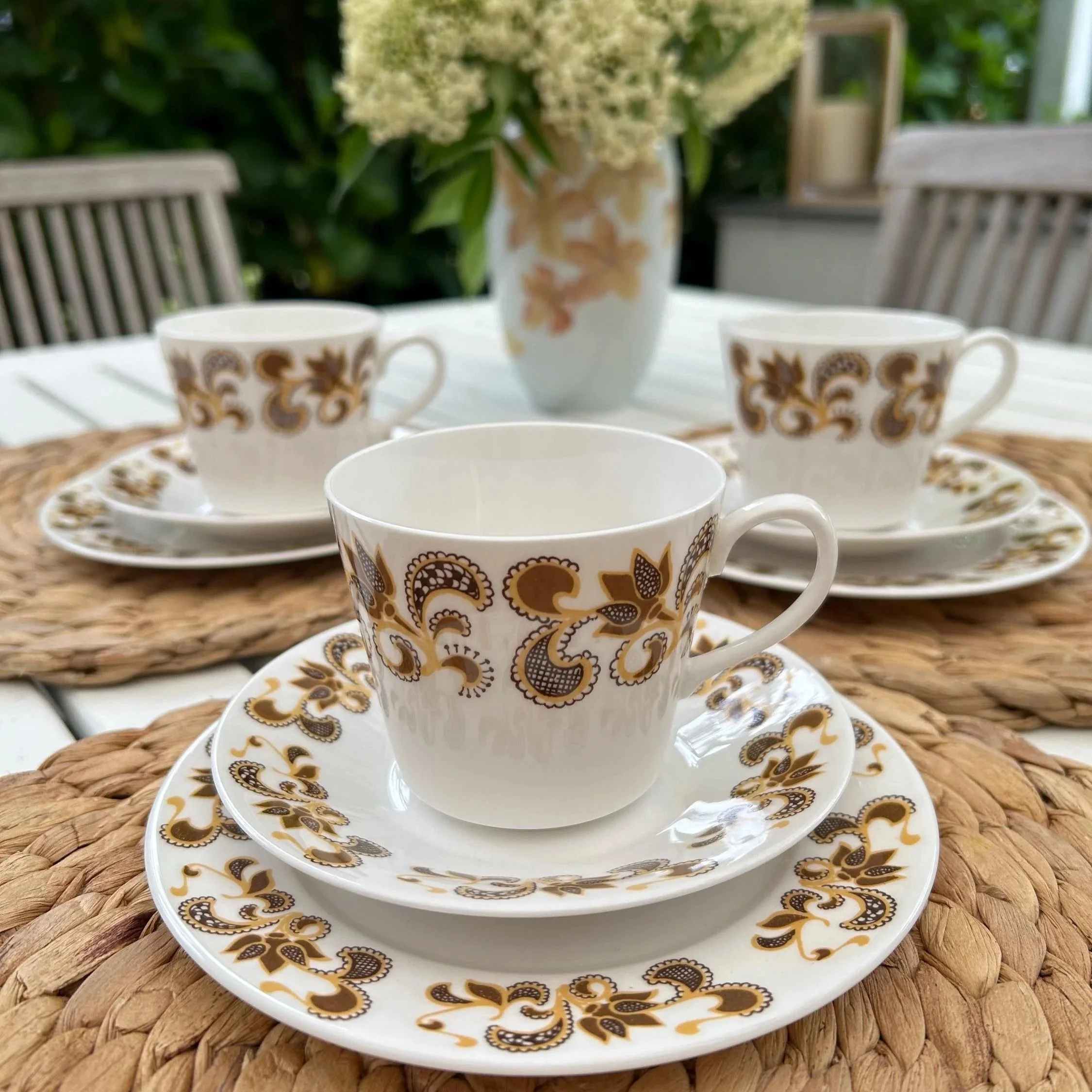 Full place setting of 3 Queen Anne trios with cups, saucers, and plates styled outdoors