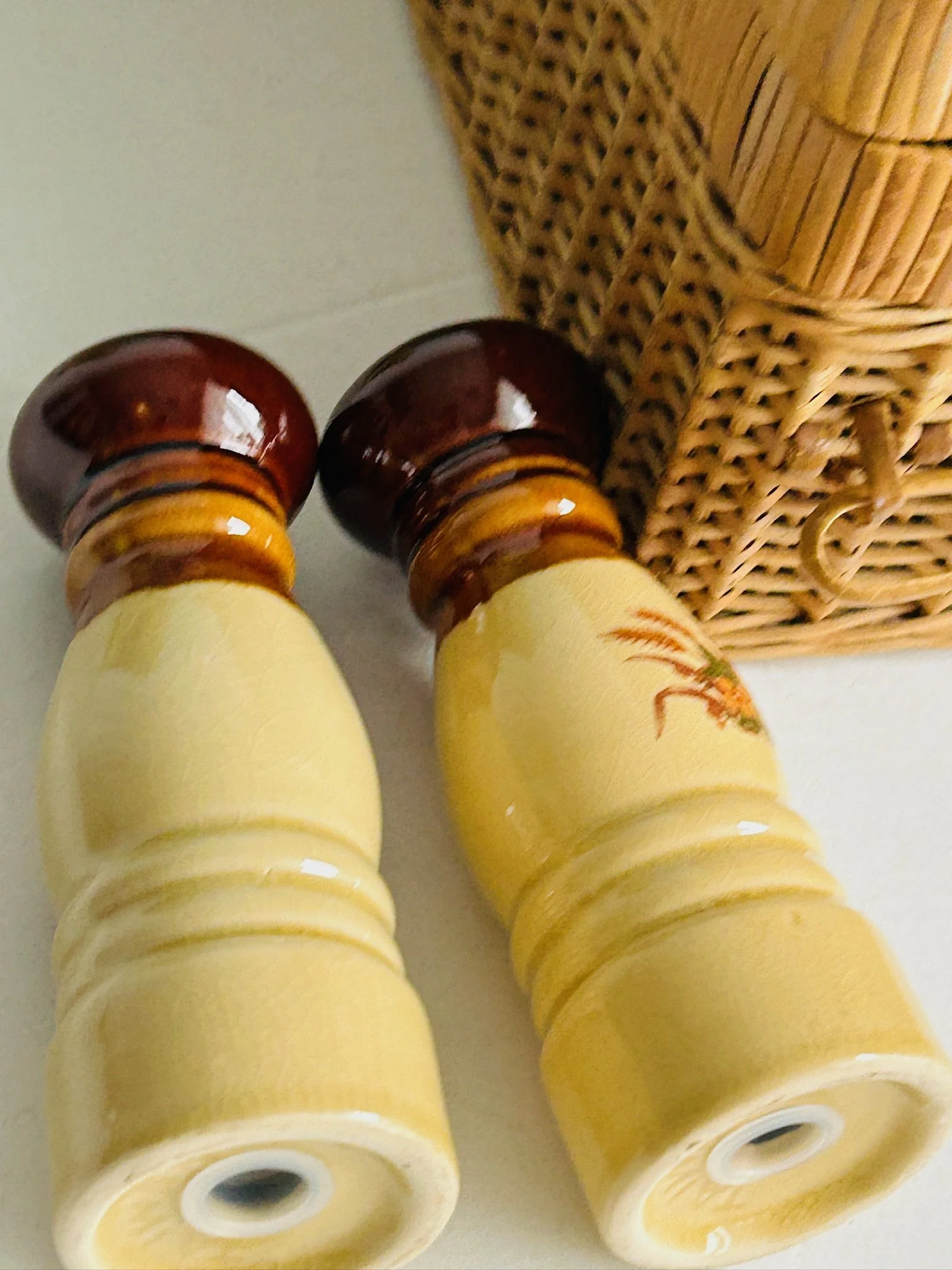 Rear angled view of both shakers laid down, showing the cream and amber glaze finish