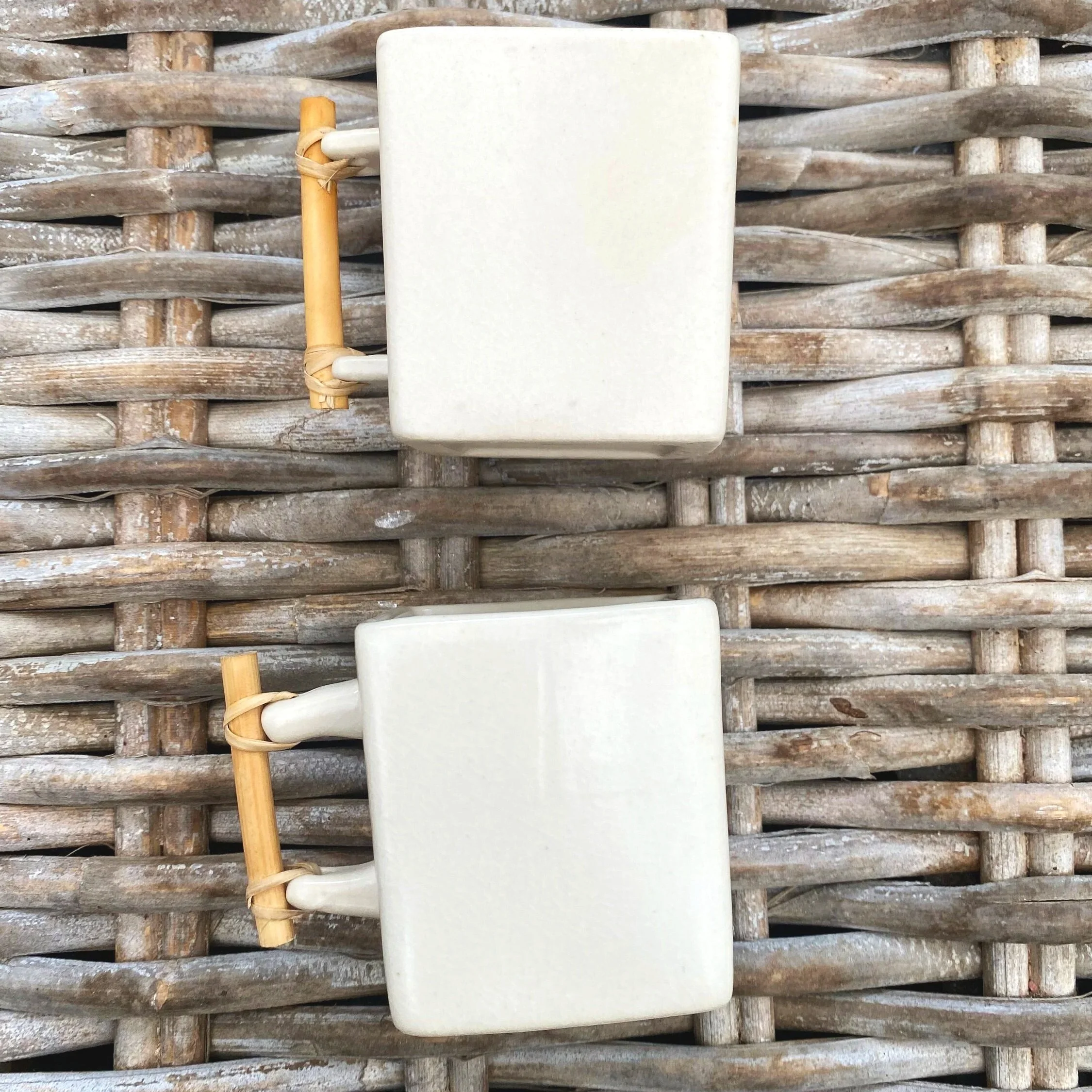 Set of two "Oltrefrontiera" cups placed side-by-side on natural wicker background