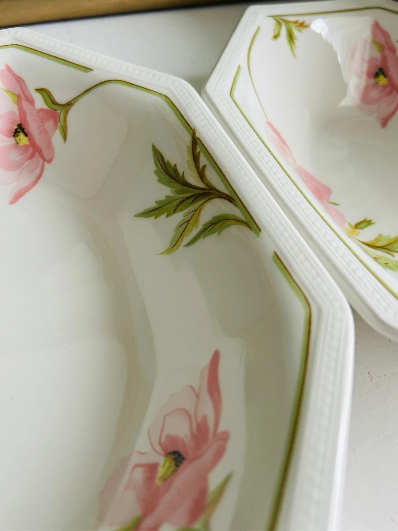 Detail of the floral pattern and textured rim, highlighting the pink blossom and leafy green stems.
