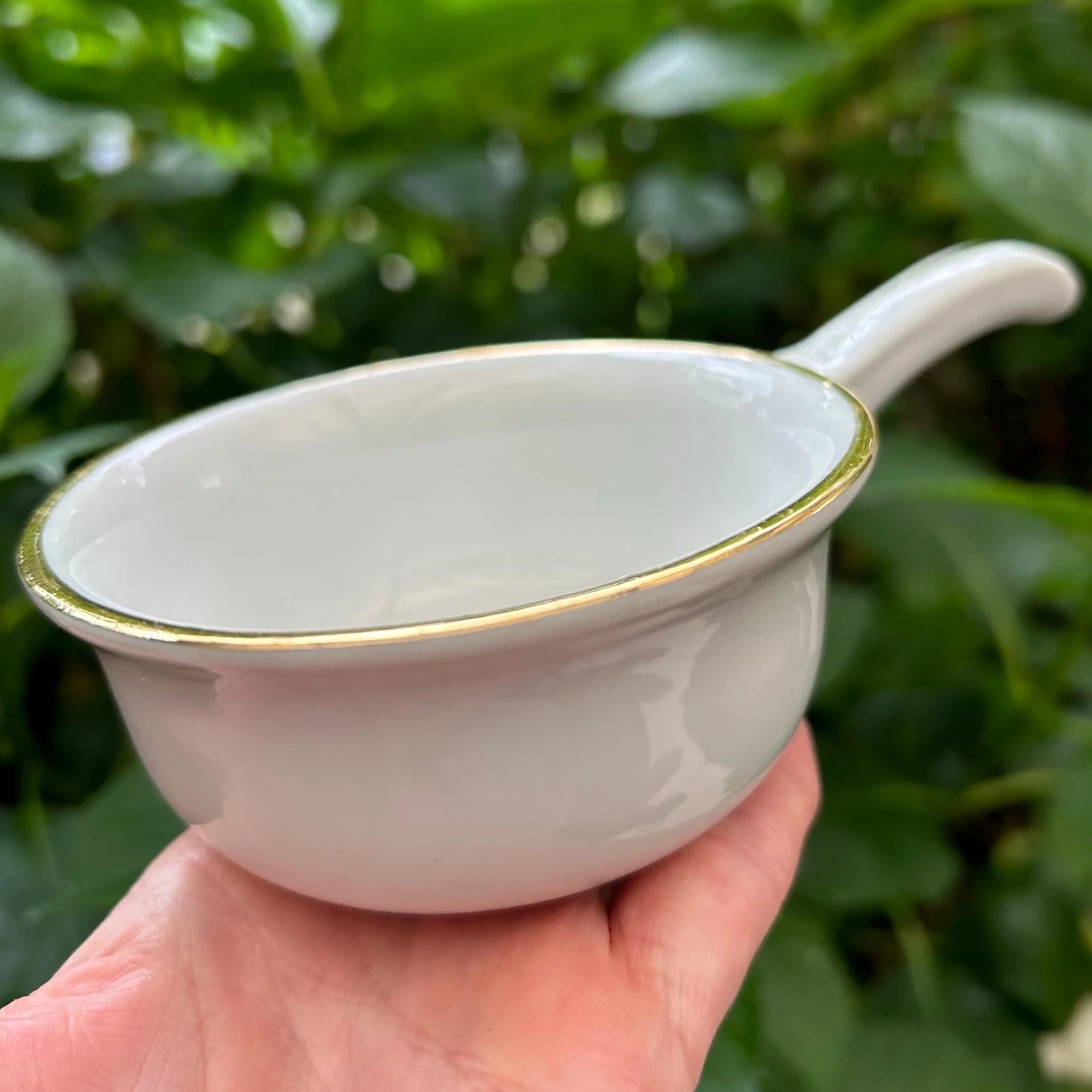 Side view of single cocotte showing gold-trimmed edge and smooth white glaze