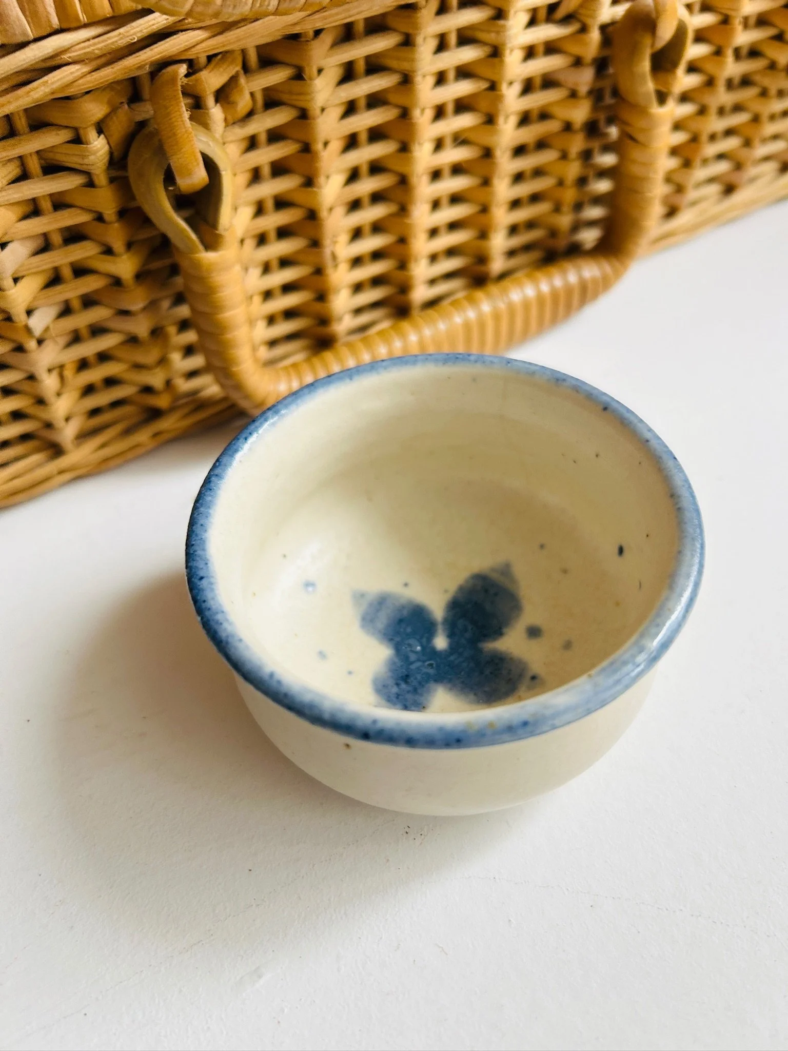 Close-up top view of the ceramic bowl held in hand, showing the interior floral detail and blue rim