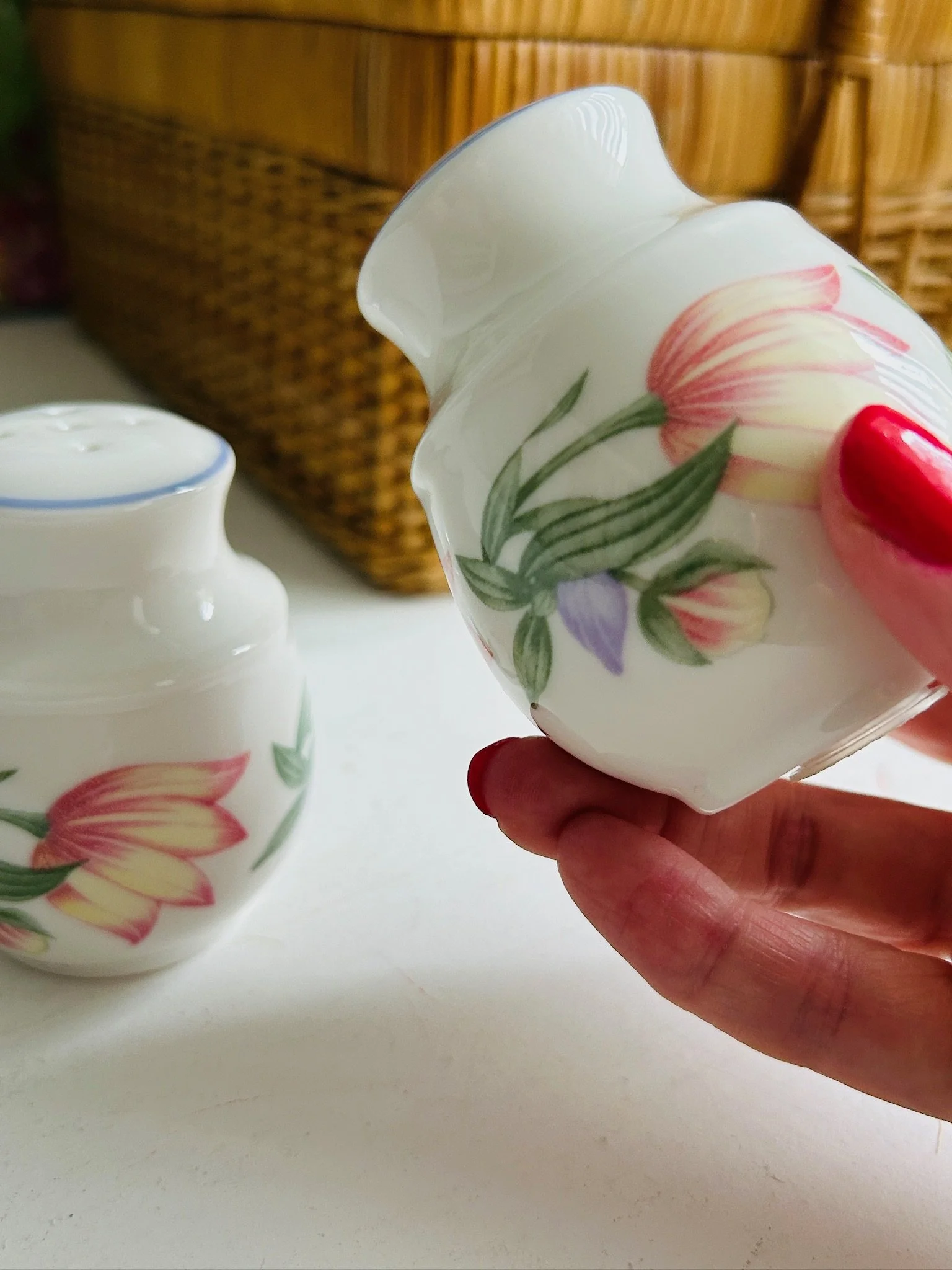Single shaker held sideways in hand, showing the floral decoration across the curved body