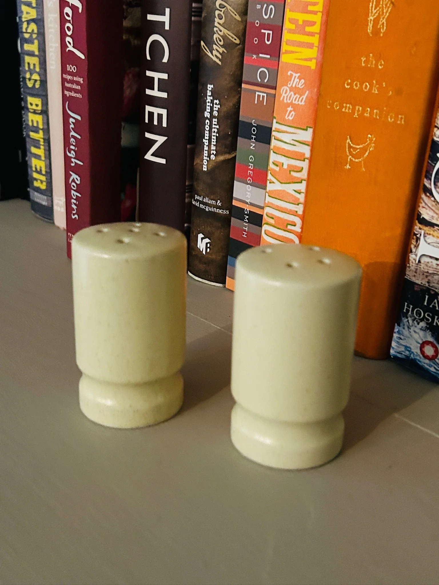 Pair of Japanese ceramic shakers styled on a shelf with books behind, showing their different hole patterns