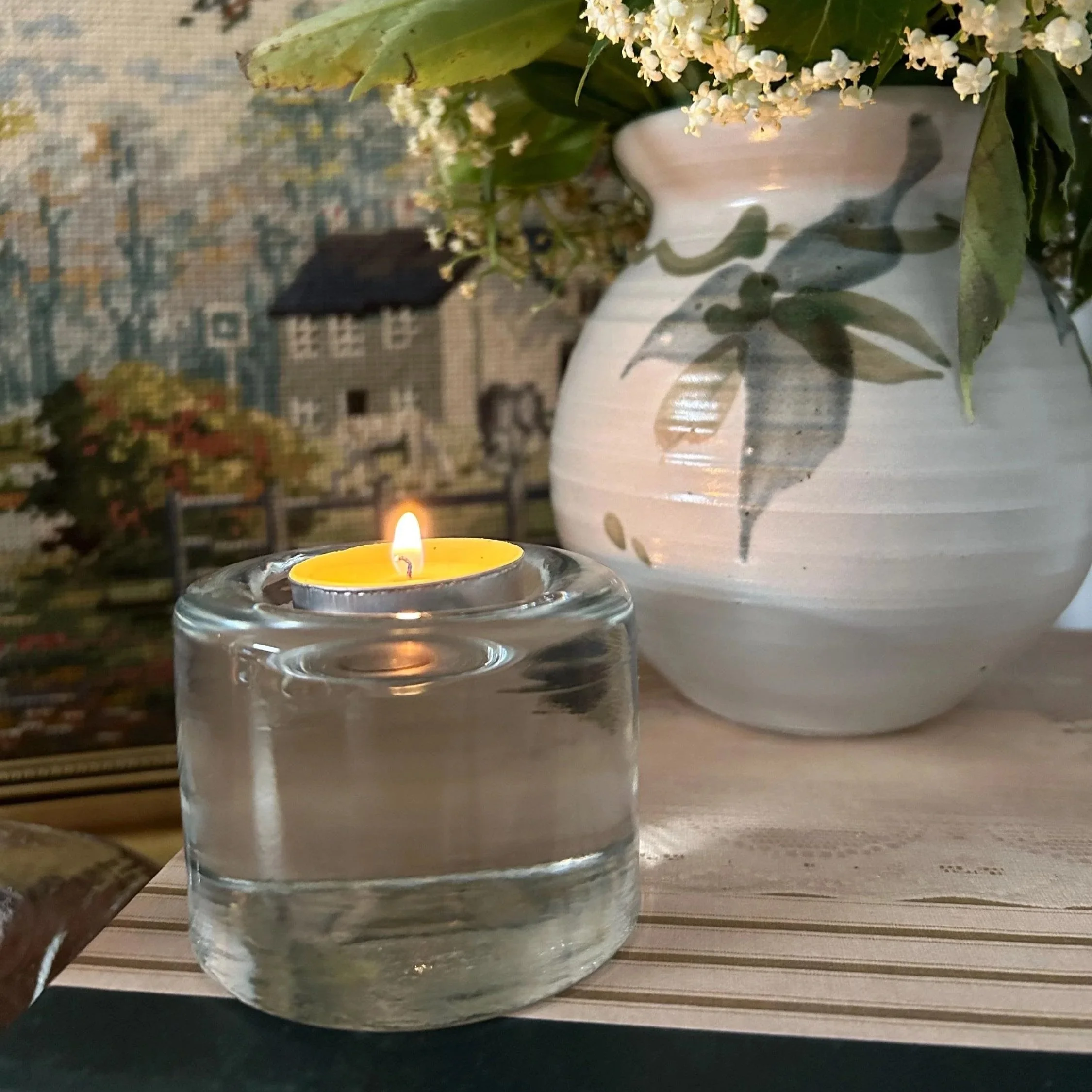 Vintage Wiesenthalhütte glass tea light holder styled with a lit candle beside books and a vase of flowers