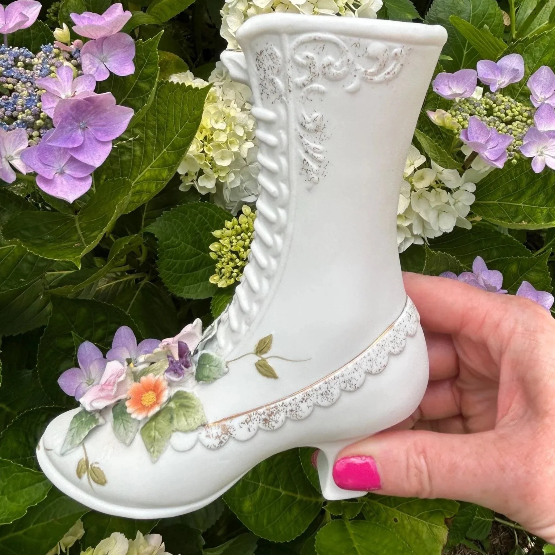 Lefton KW4740 porcelain boot vase displayed outdoors among hydrangeas, showing floral details