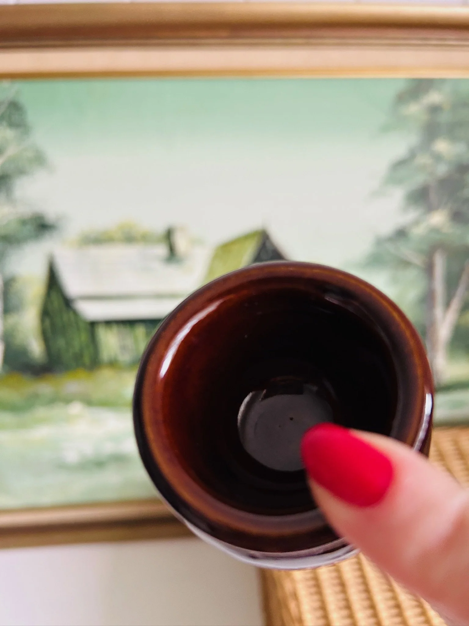 Front view of the small Moira stoneware pot on a white surface with framed artwork behind