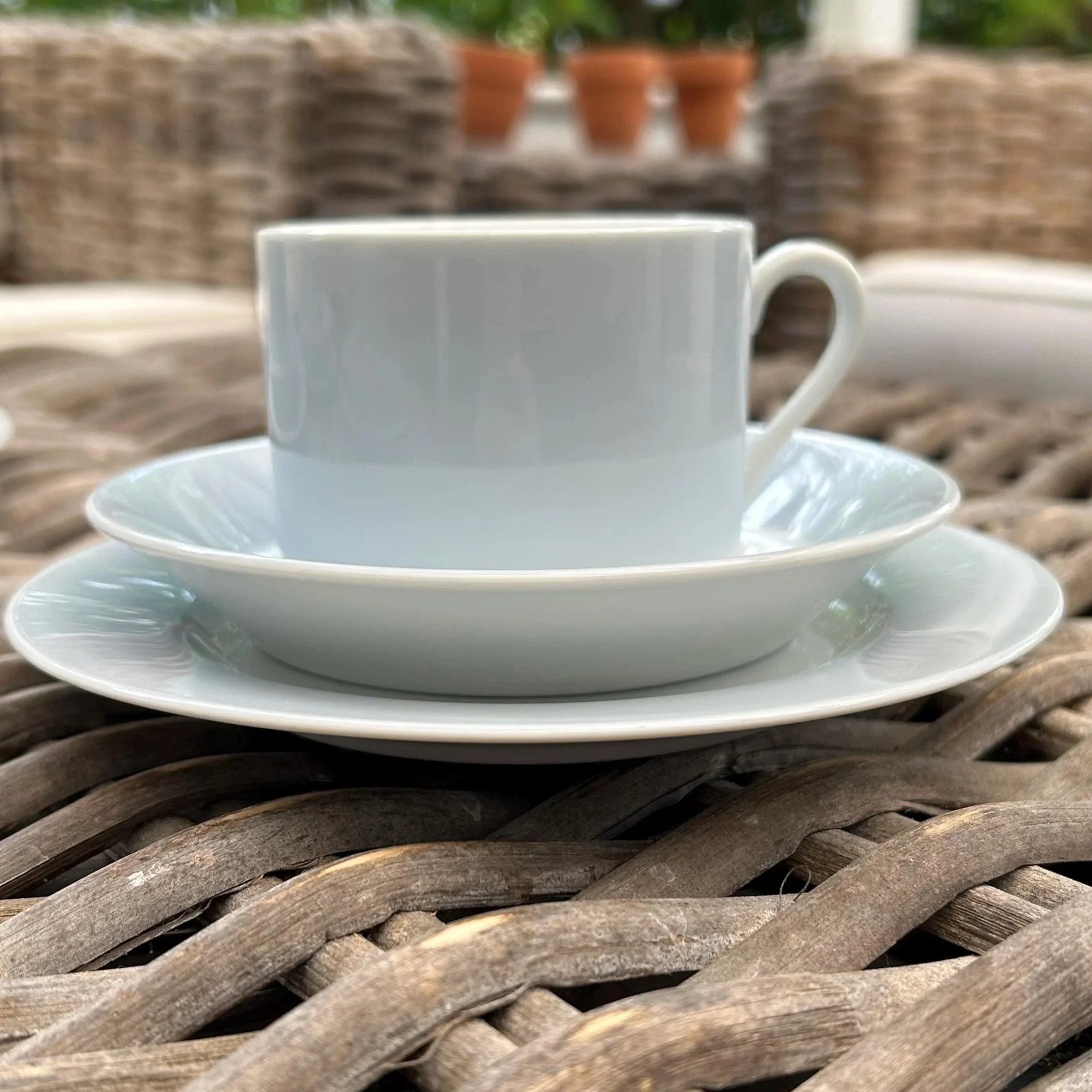 Side view showing pastel blue flat cup stacked on saucer and bread plate