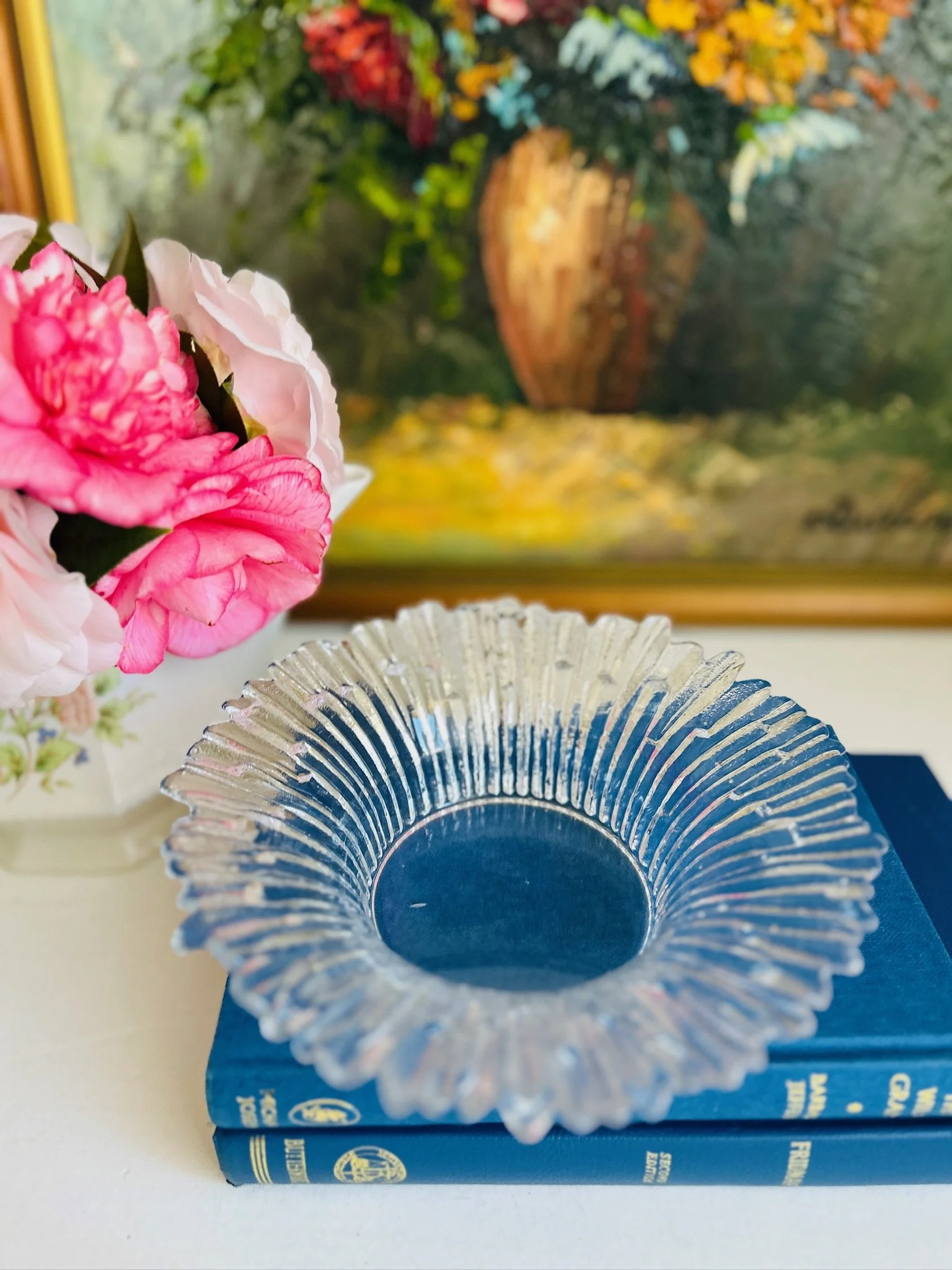 Scandinavian Modern glass dish resting on blue vintage books, viewed from above showing the central well