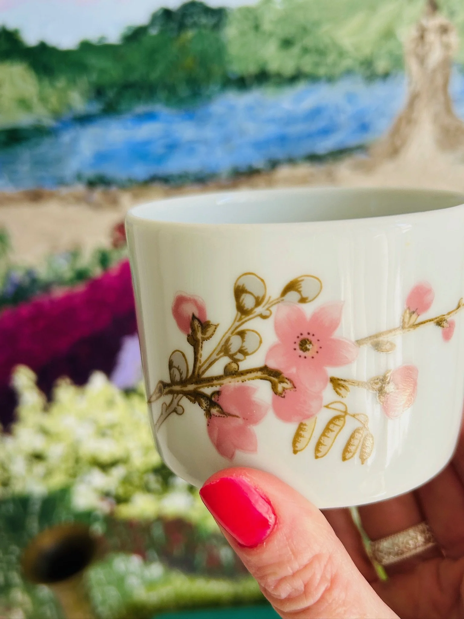 Side view of the porcelain trinket bowl held in hand, showing the floral decoration and gold trim around the lid