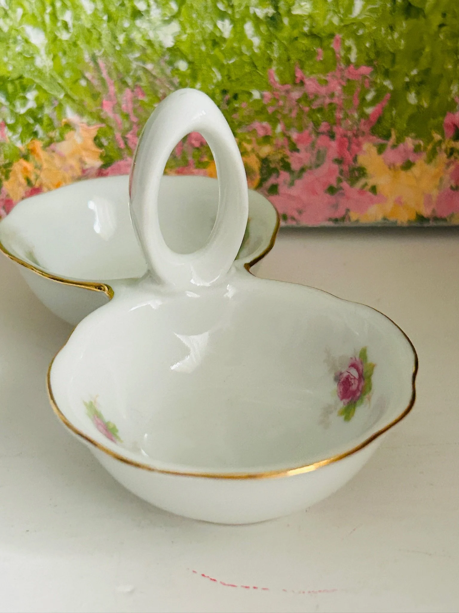 Angled close-up of one bowl and centre handle showing white porcelain and floral detail