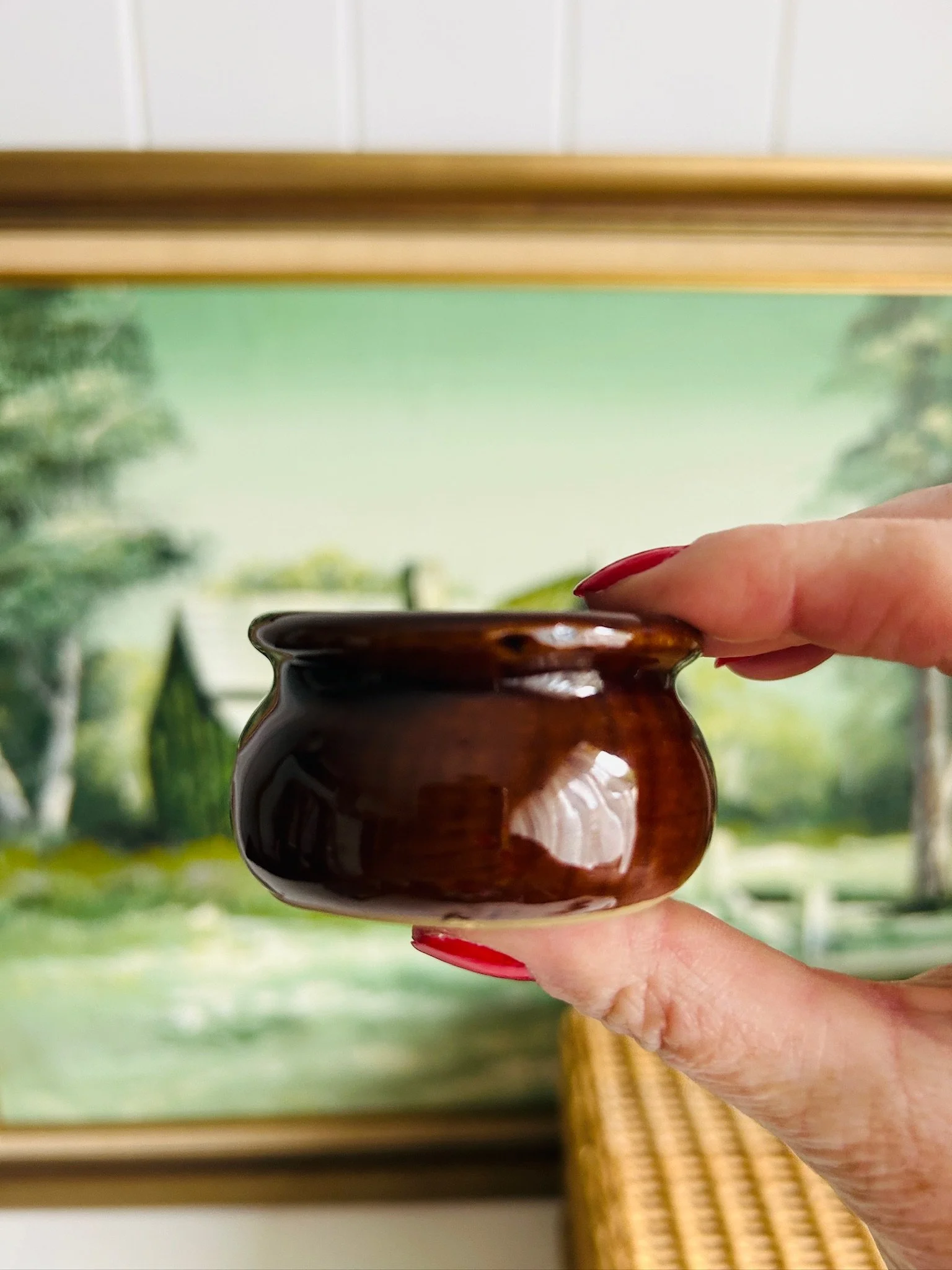 Side profile of the miniature stoneware pot held between fingers to show scale