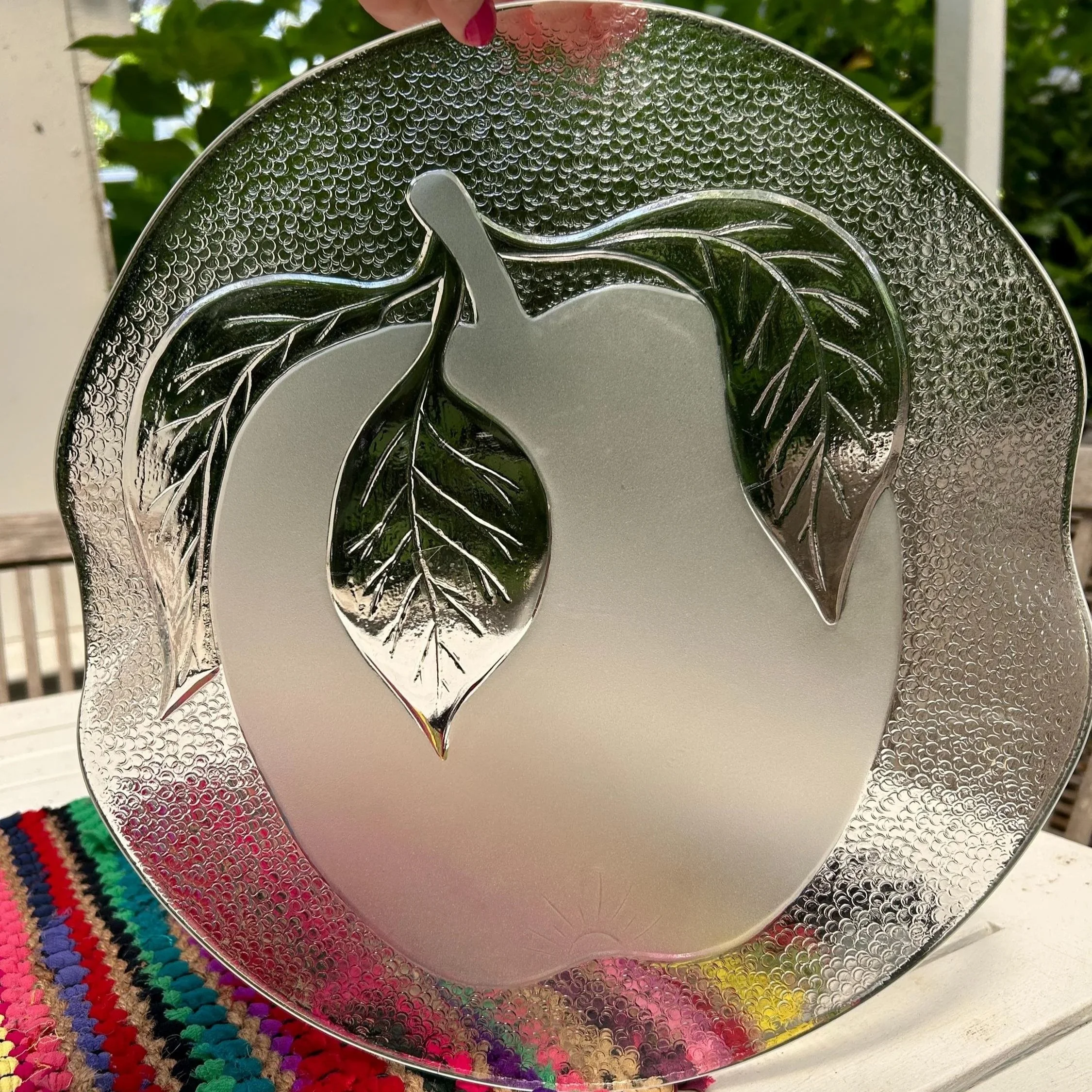 Full front view of platter with apple and leaf motif against outdoor background.