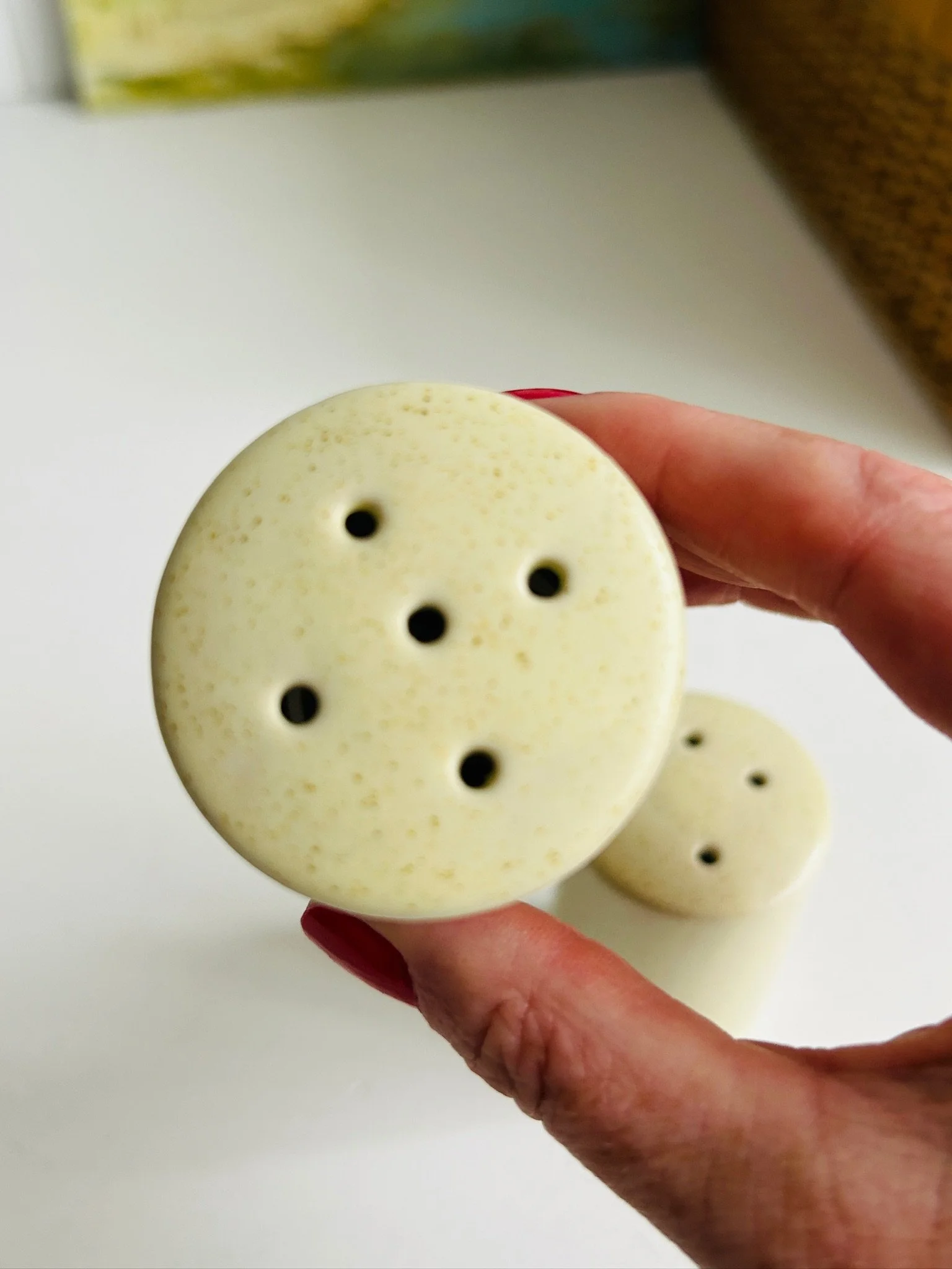Close-up of the matching shaker held in hand, showing the five-hole top and speckled cream finish