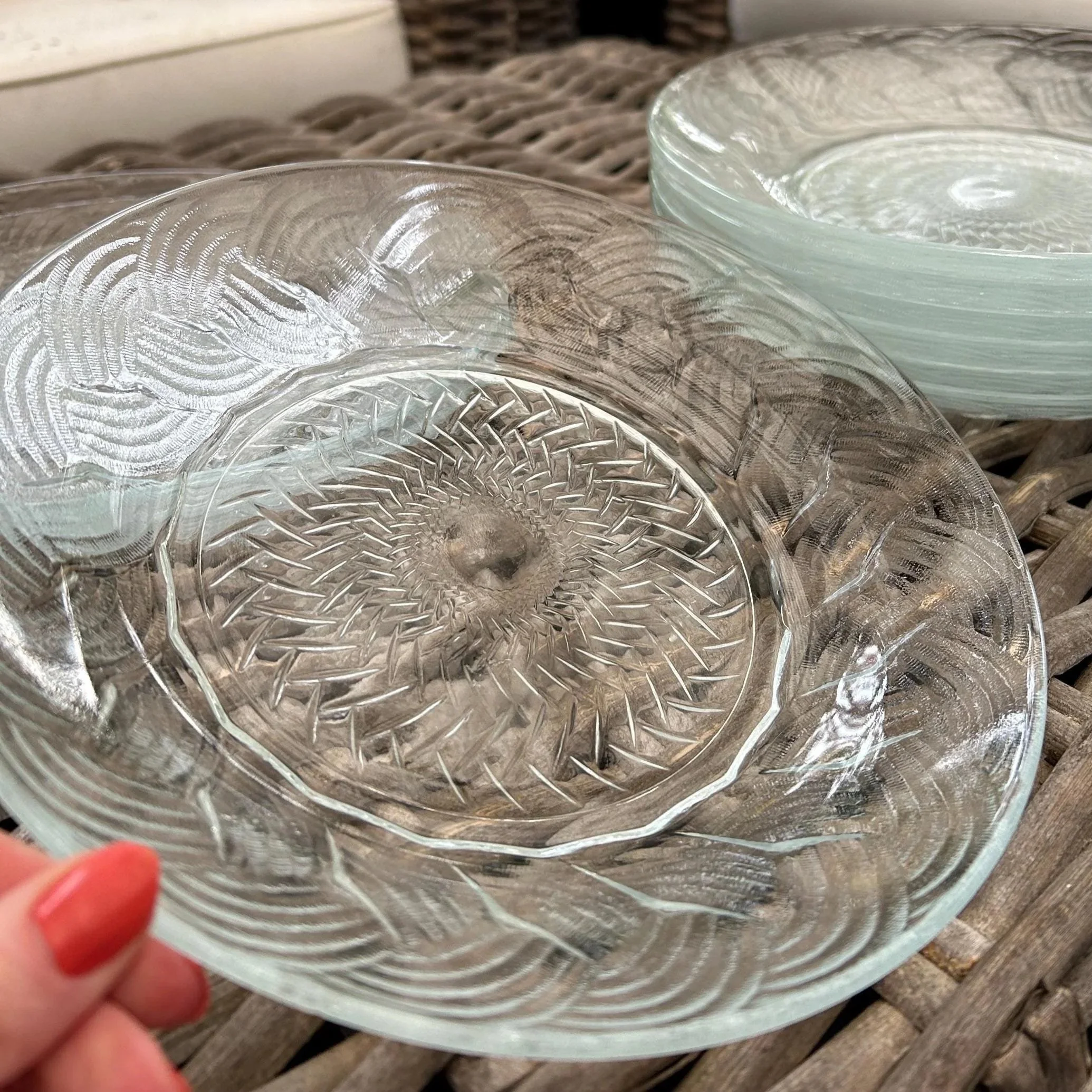 Set of 9 textured glass bowls stacked on a wicker table with natural light