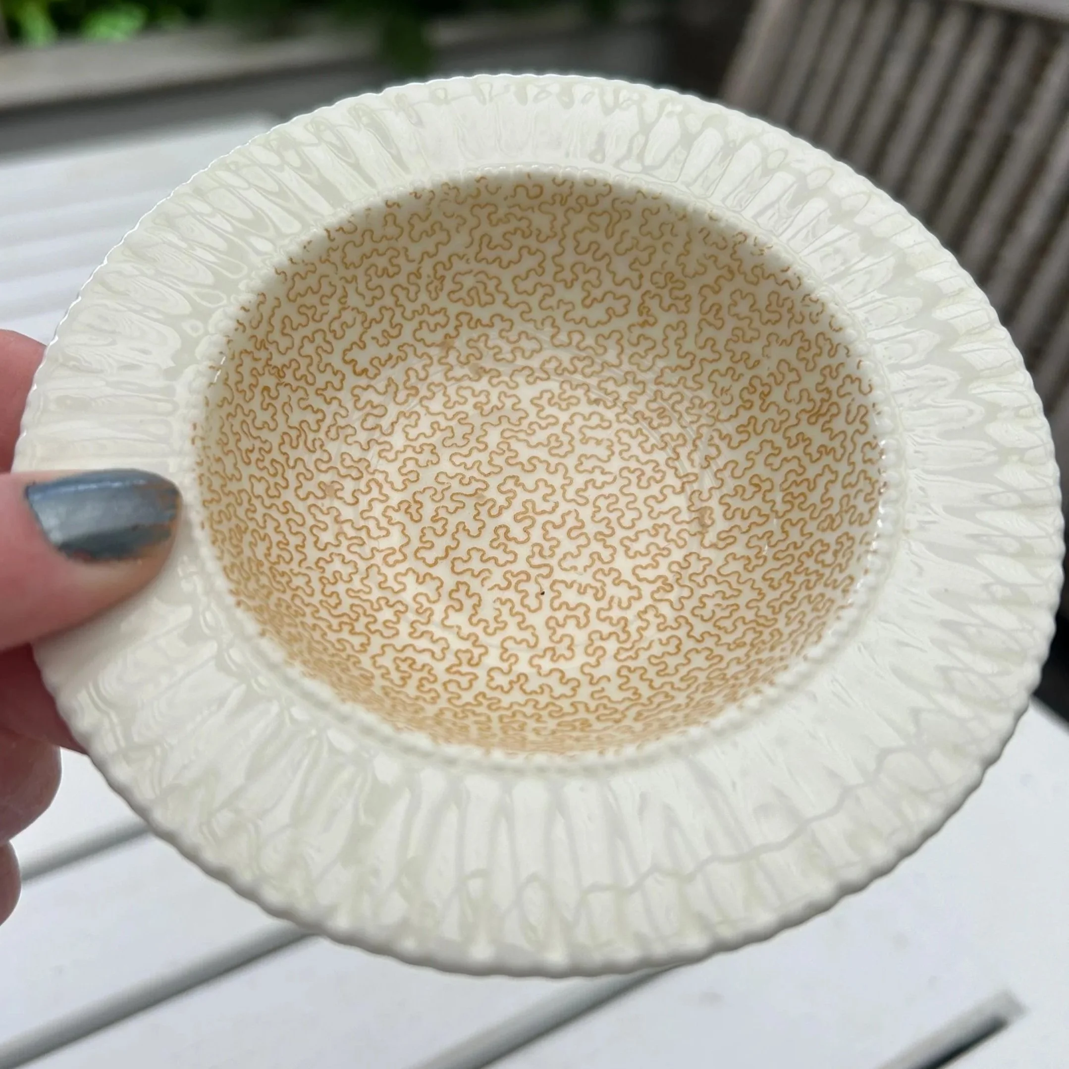 Hand holding the Royal Doulton dish showing the full golden maze pattern and textured rim