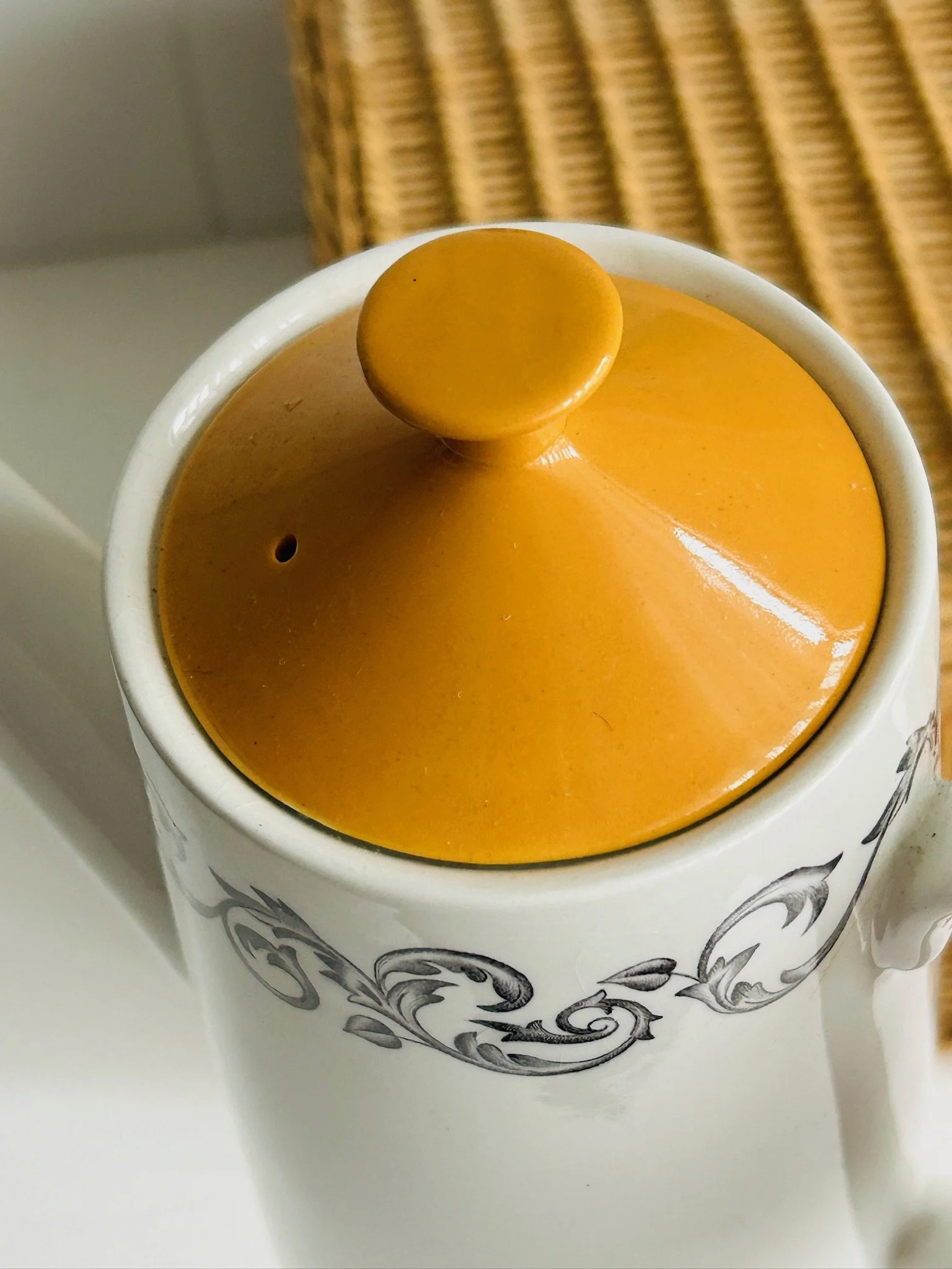 Close-up of the bright orange lid seated in the pot, highlighting the sculptural knob, vent hole, and glossy finish.