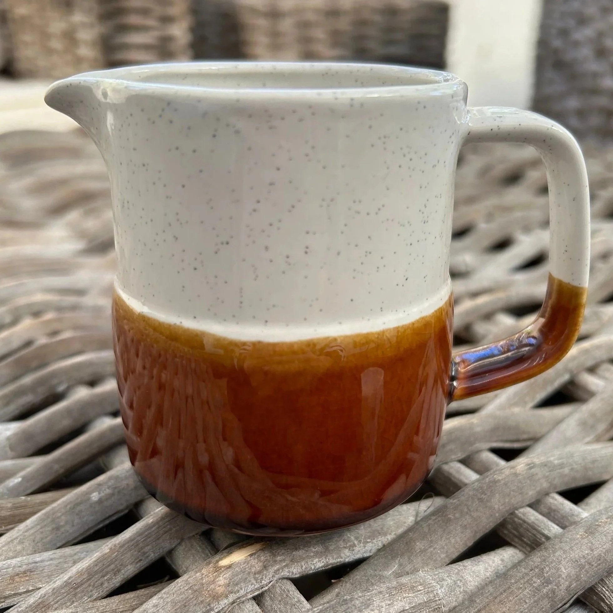 Vintage ceramic creamer jug with white speckled top and brown glazed base, shown from the front angled view