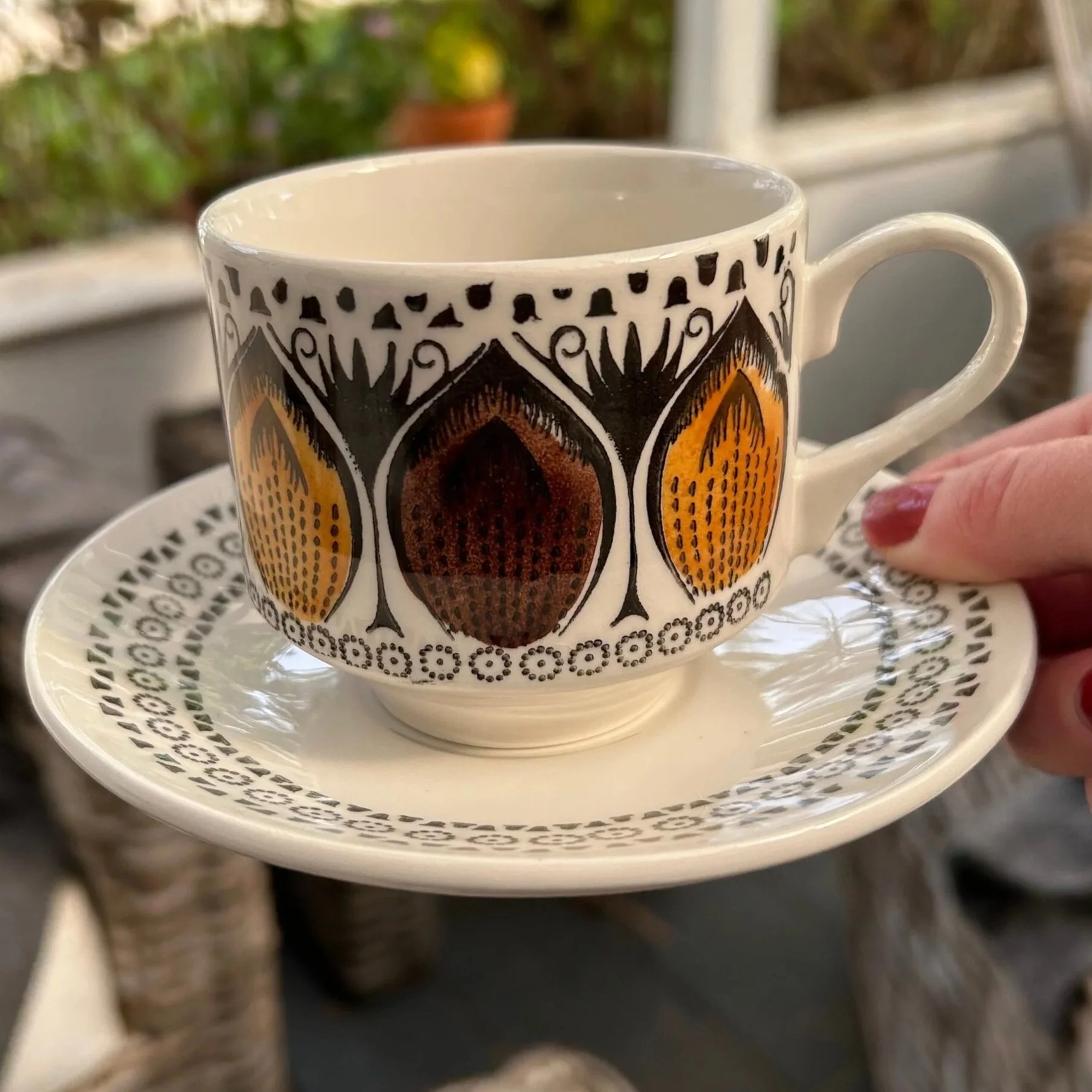 Close-up of one cup and saucer showing the hand-painted pattern and underglaze finish