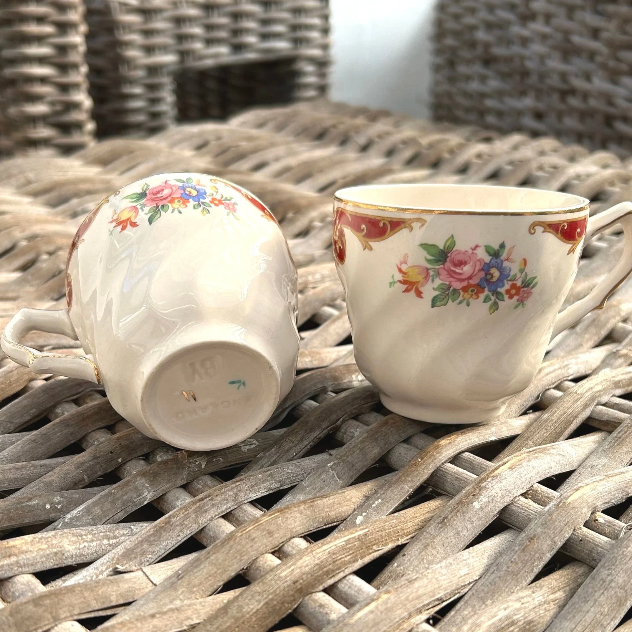 Two cups lying on side showing floral motif and base stamp