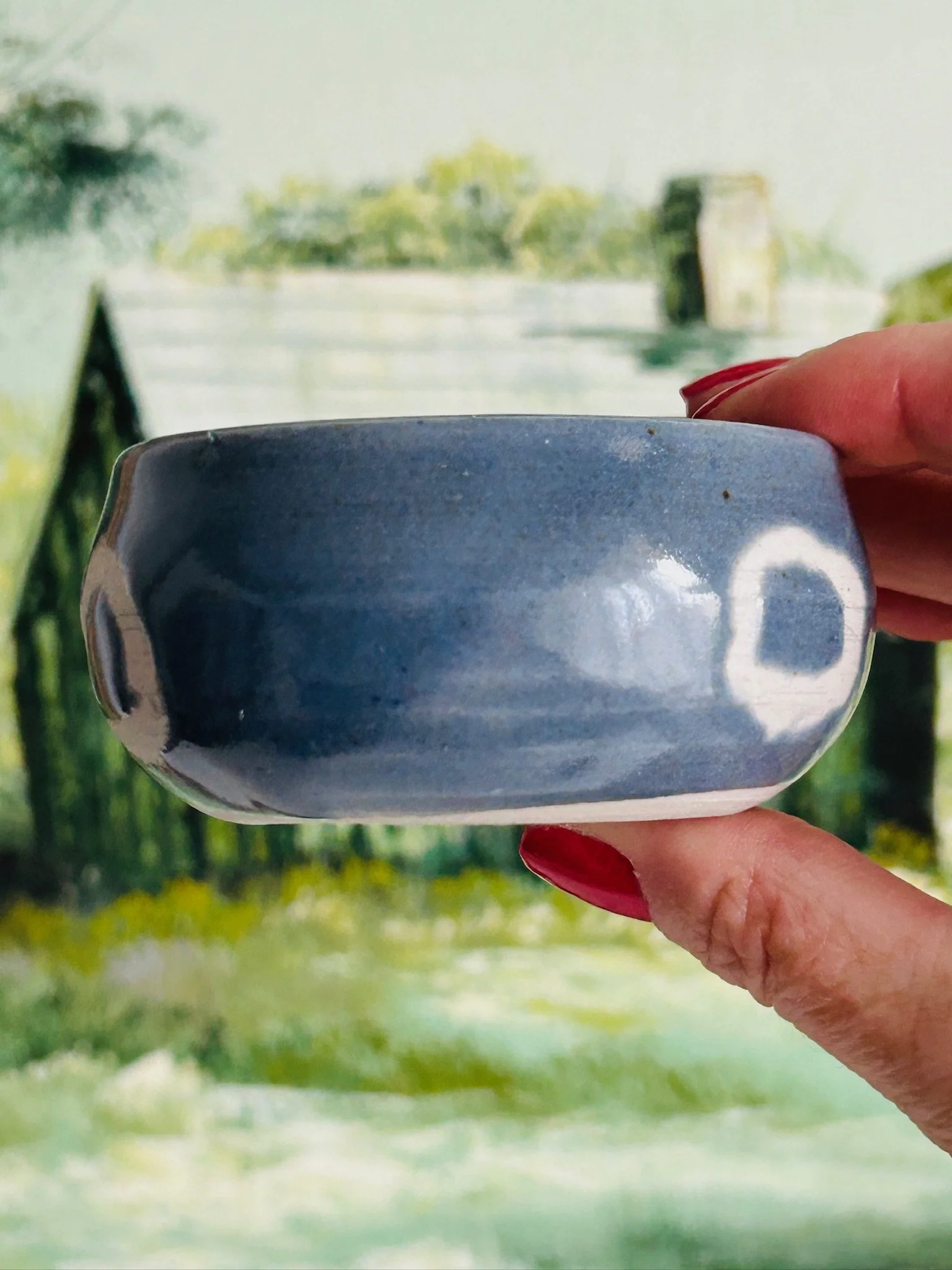 Side angle of the ceramic bowl held in hand, showing the rounded silhouette and artisan glaze finish